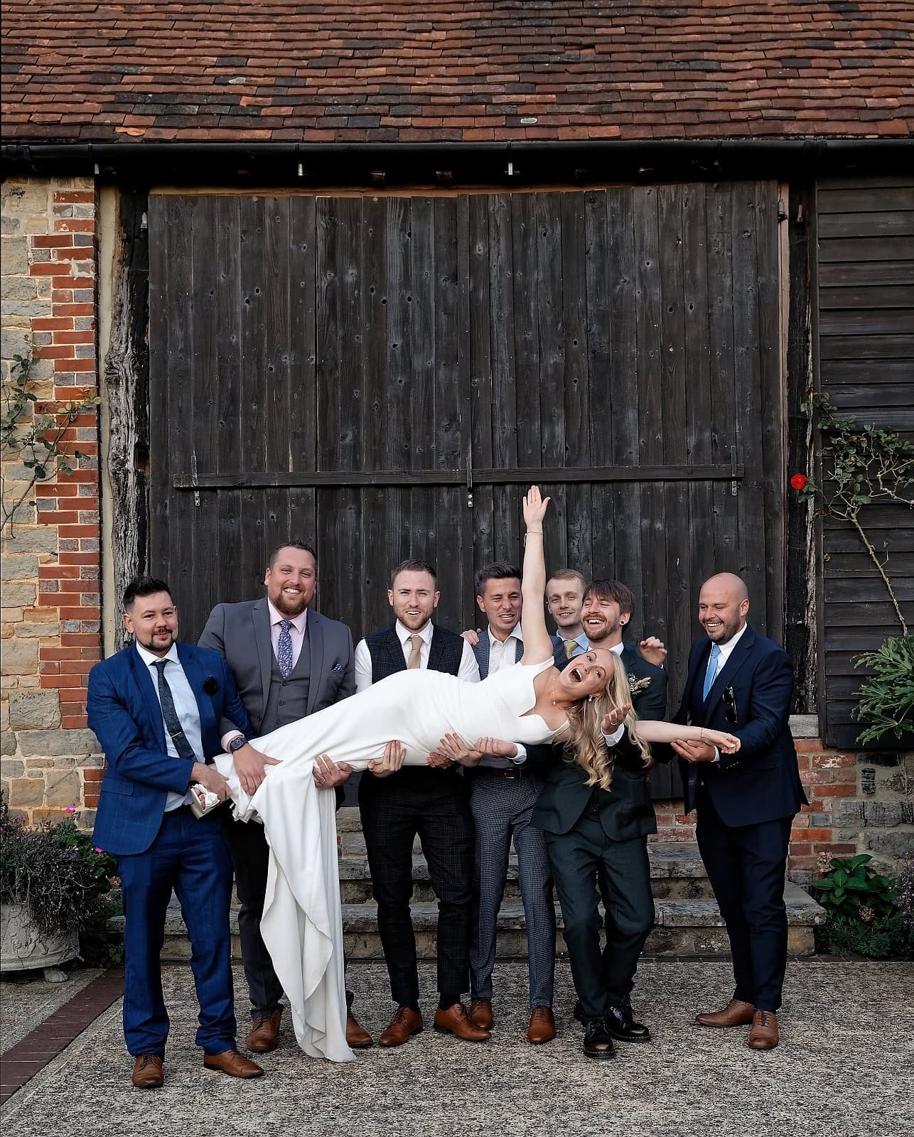Bride lifted into the air by the groomsmen outside the barn doors at Fitzleroi Barn