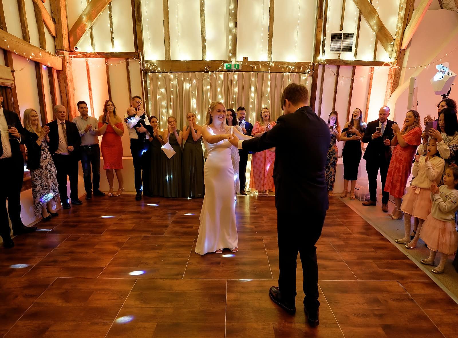 Fitzleroi Barn wedding photography of the couple's first dance beneath fairy lights in the barn