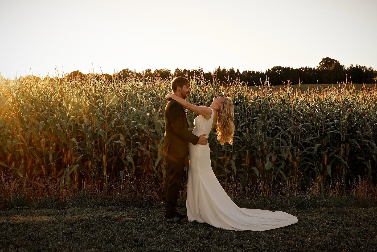 Bride and groom sharing a laugh during golden hour portraits in the fields at Fitzleroi Barn