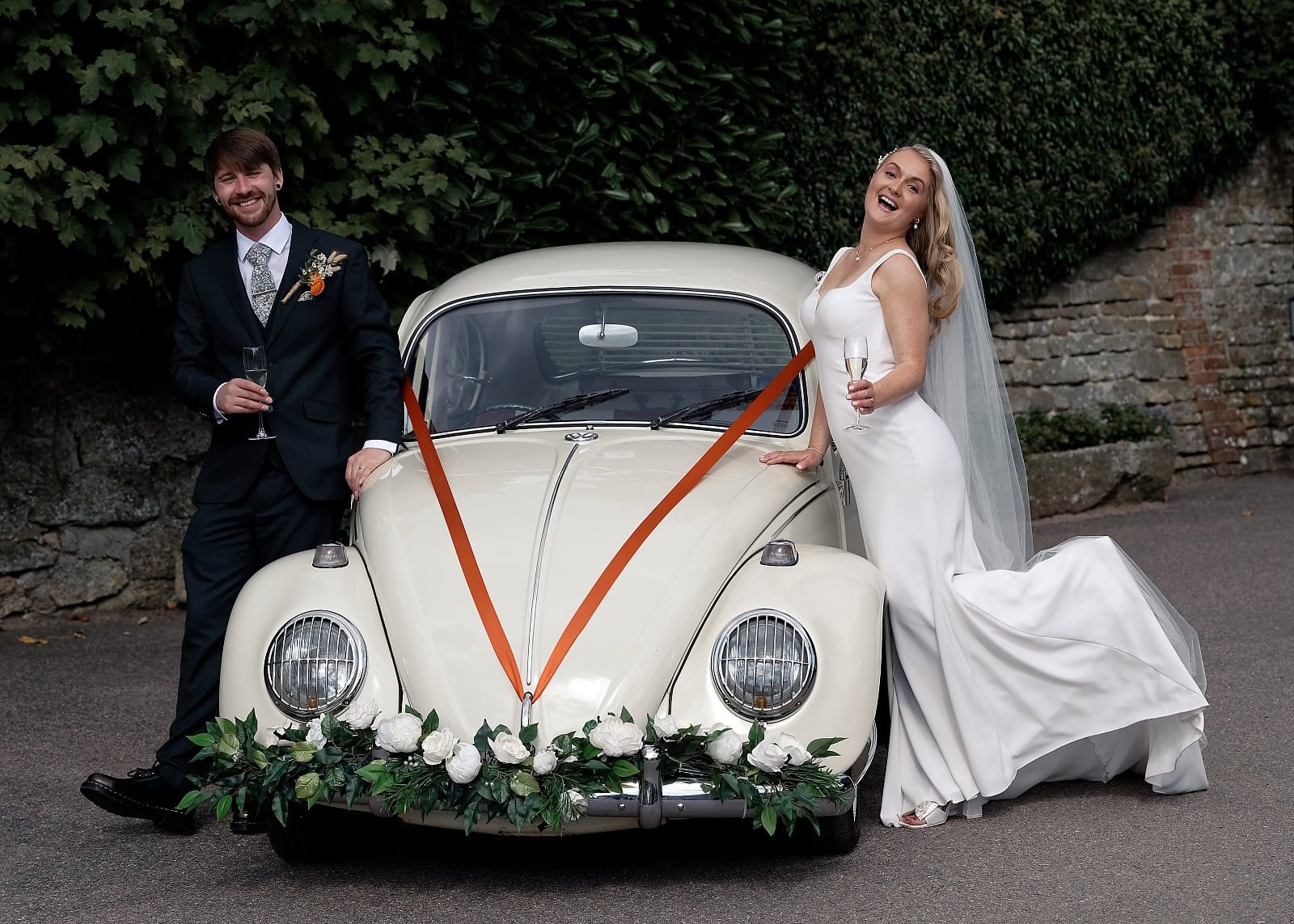 Bride and groom with a vintage cream VW Beetle wedding car at Fitzleroi Barn