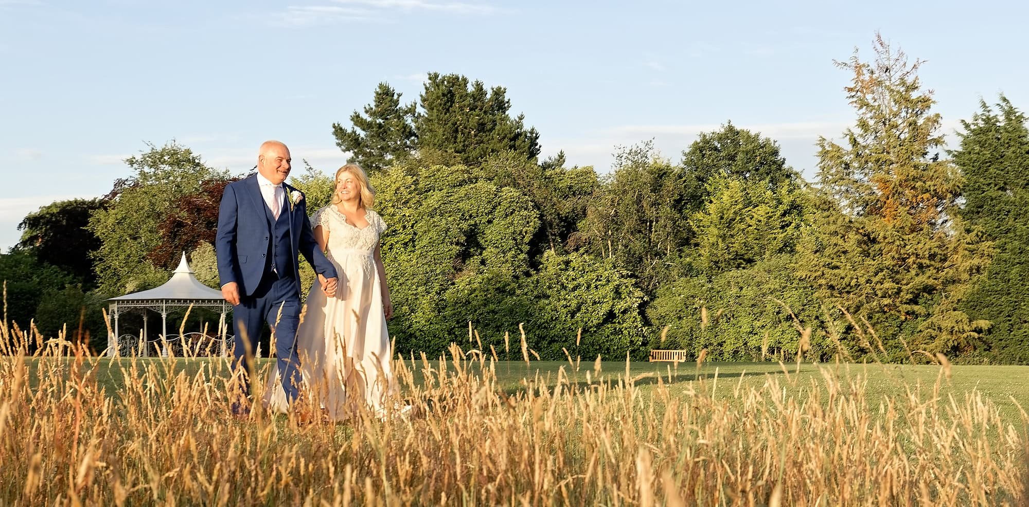 Bride and groom walking hand in hand across the lawns at South Lodge Hotel, Horsham, West Sussex