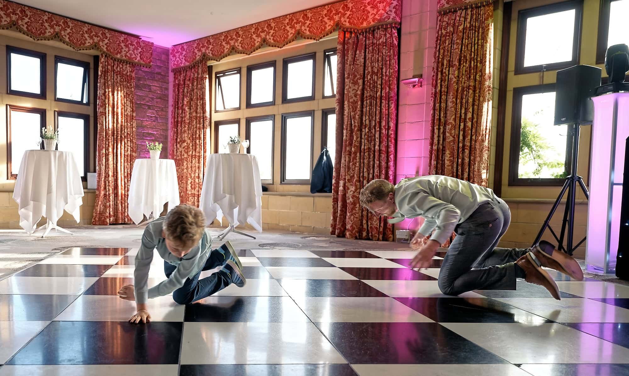 Father and son guests break dancing on the dance floor at South Lodge Hotel wedding reception, Horsham, West Sussex