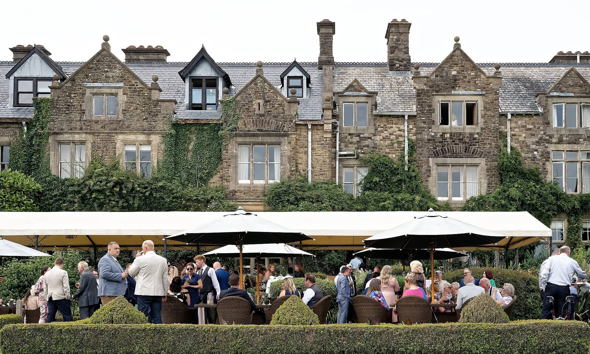 Wedding guests relaxing on the terrace at the rear of South Lodge Hotel, Horsham, West Sussex
