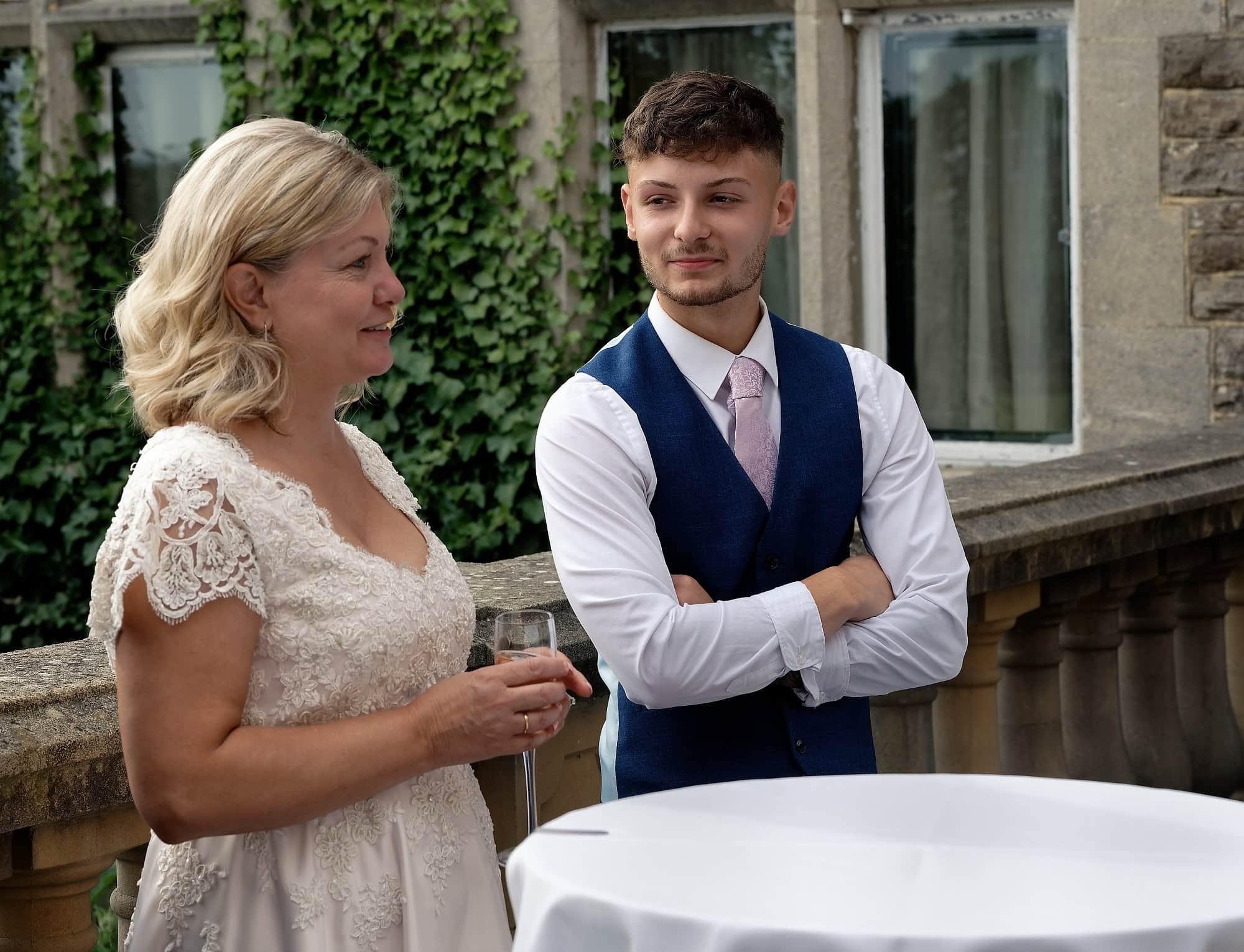 Son Joe looking fondly at his mother the bride during the groom's speech on the terrace at South Lodge, Horsham