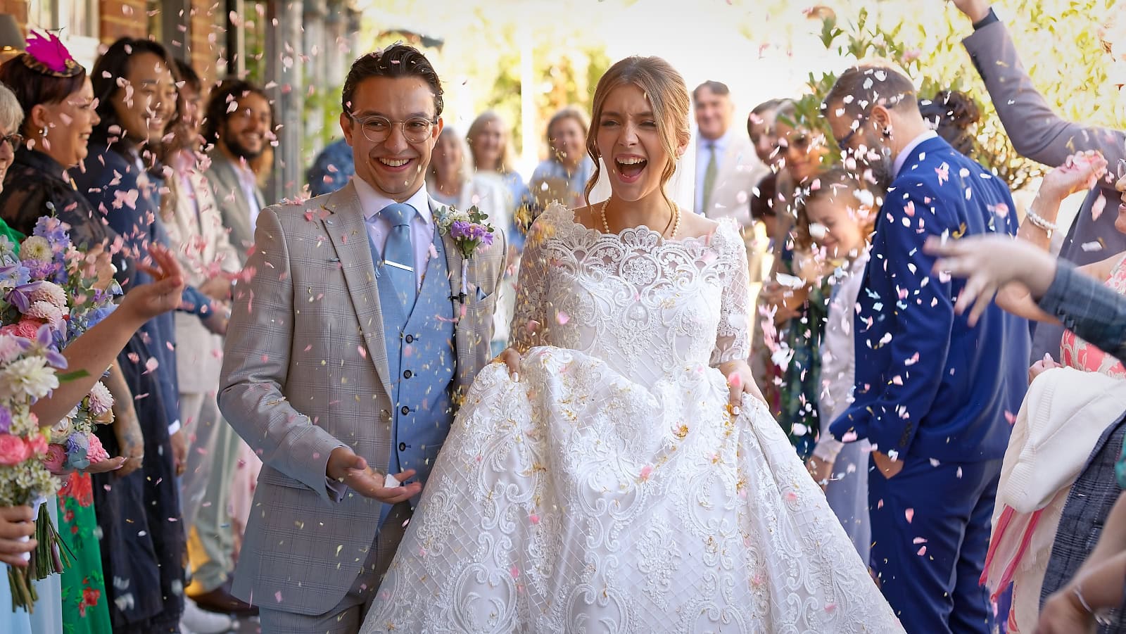 Bride and groom laughing as they walk through confetti at Trading Boundaries wedding Sussex
