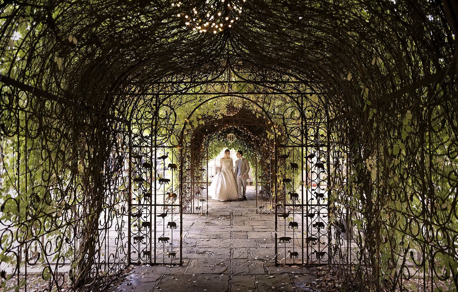Bride and groom walking through garden archway at Trading Boundaries wedding venue Sussex