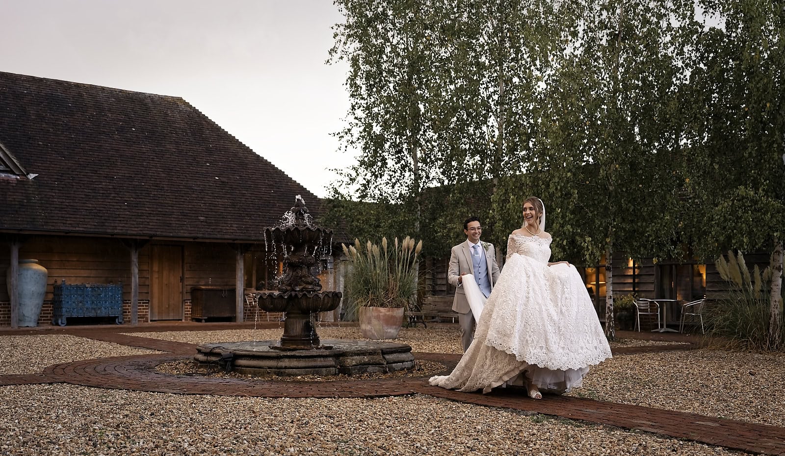 Bride and groom walking by fountain at Trading Boundaries wedding venue Sussex