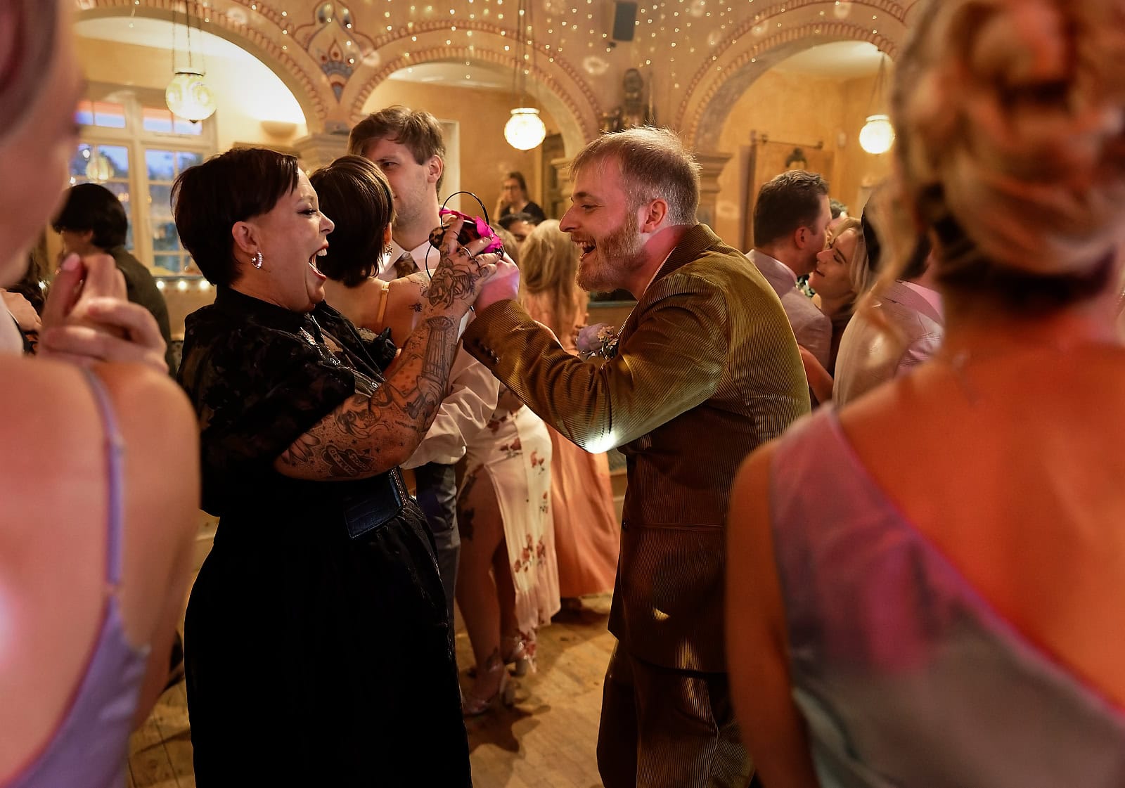 Candid moment of wedding guests dancing and laughing at reception