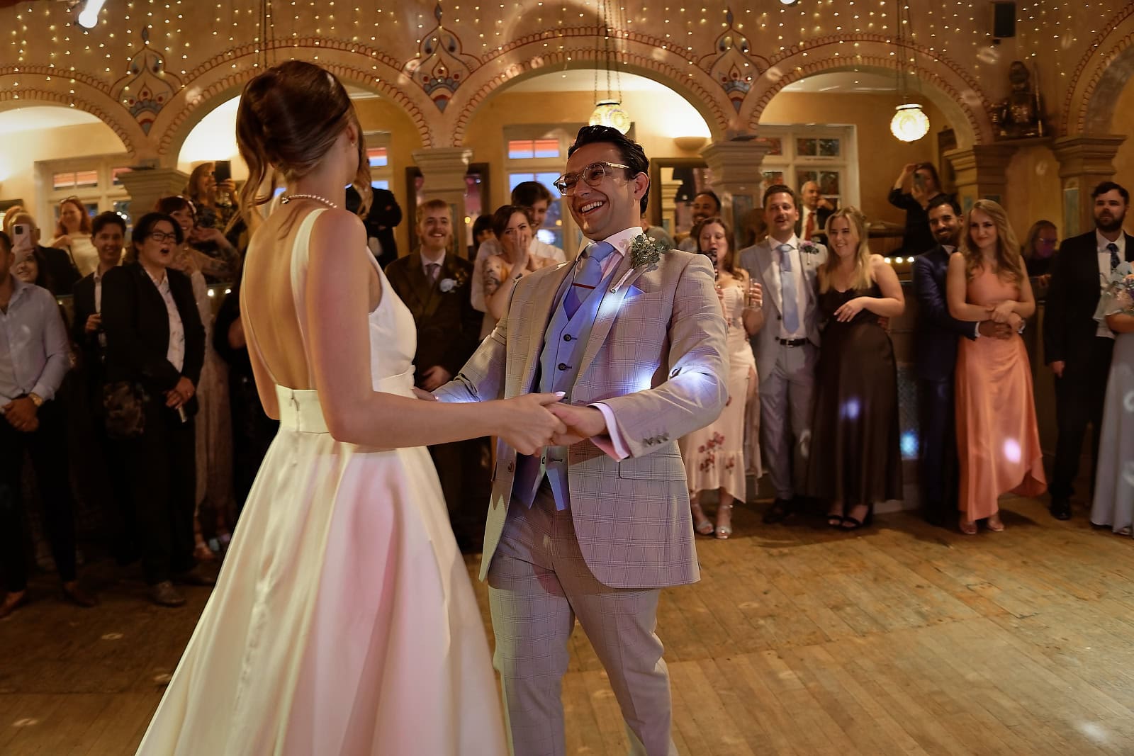 Bride and groom dancing during first dance with guests watching at Trading Boundaries Sussex