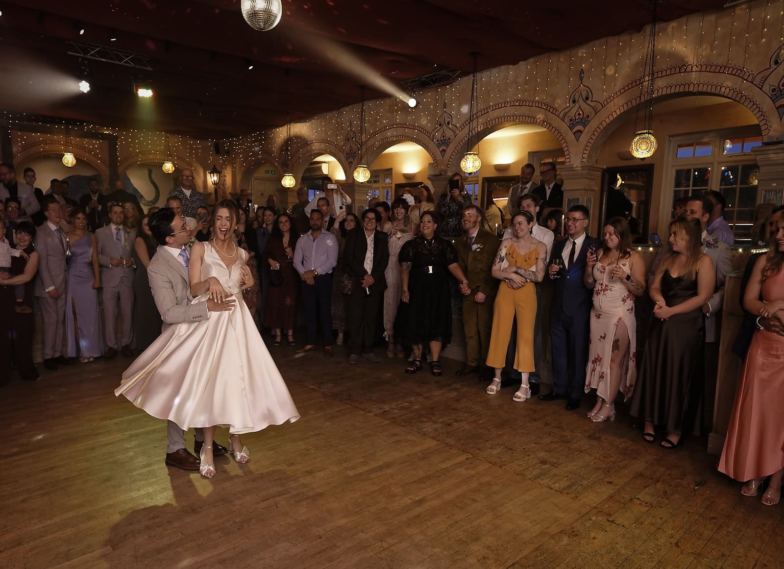 Wide view of bride and groom first dance with guests watching at Trading Boundaries Sussex