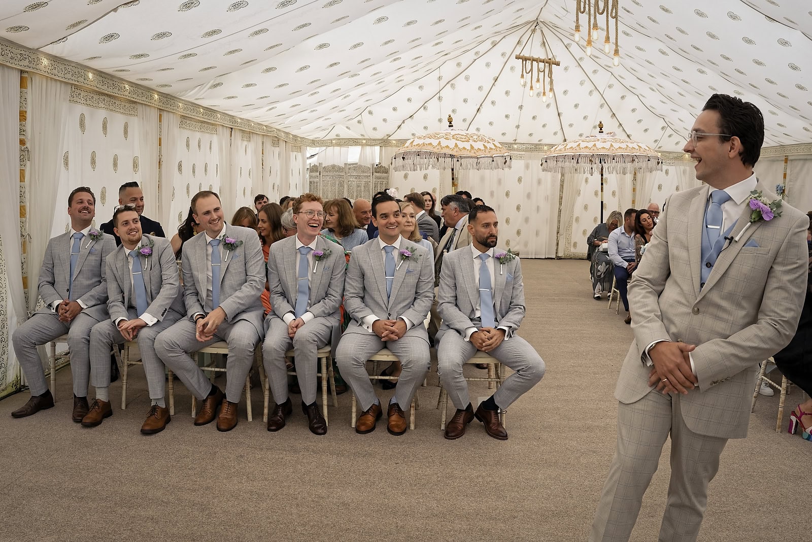Groom and groomsmen reacting during wedding ceremony at Trading Boundaries Sussex