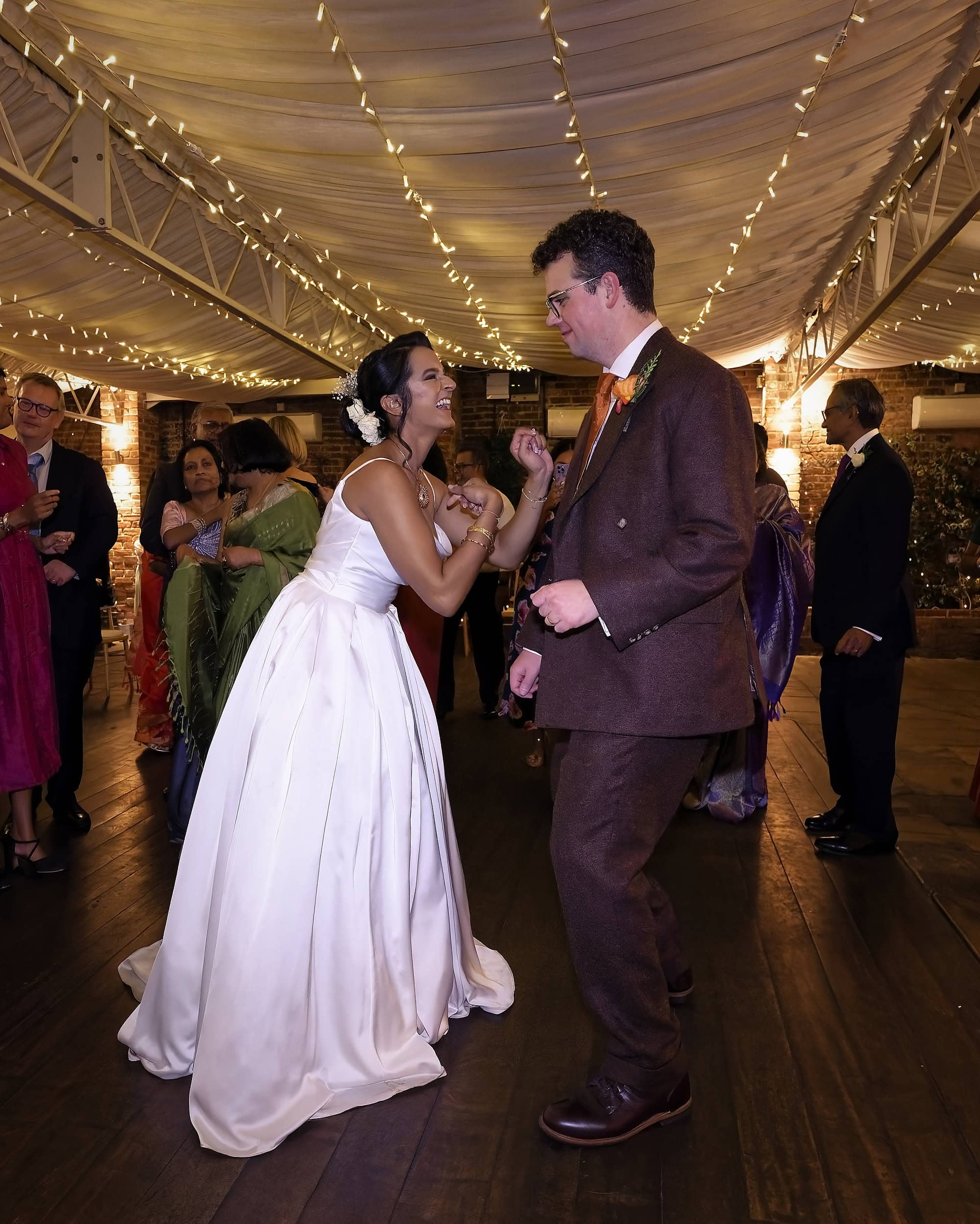 Bride and groom laughing and dancing together in the Orangery at Northbrook Park wedding venue in Hampshire by Andy Kerr Photography