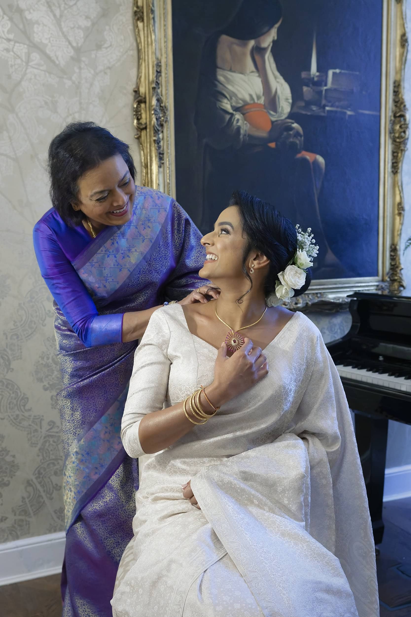 Bride having necklace fastened by her mother in the manor house at Northbrook Park wedding venue in Hampshire by Andy Kerr Photography