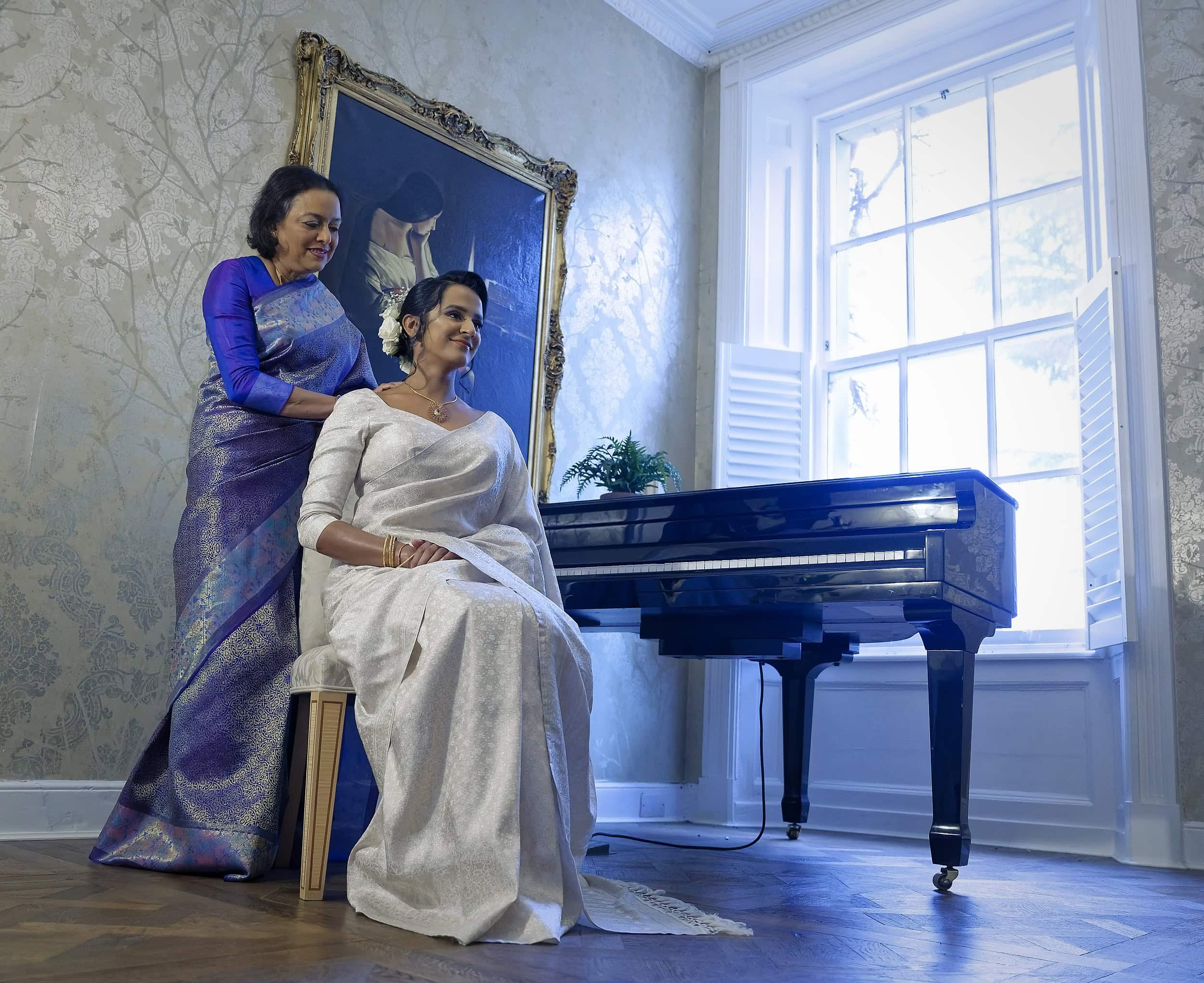 Bride and mother portrait by the grand piano in the manor house at Northbrook Park wedding venue in Hampshire by Andy Kerr Photography