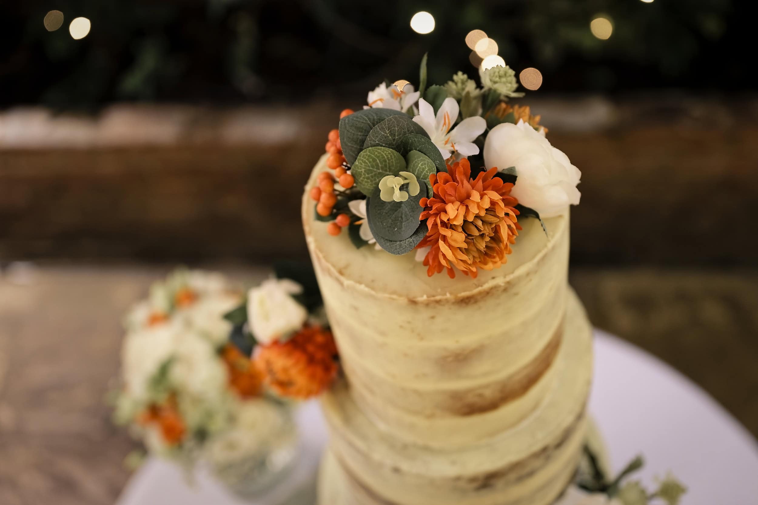 Wedding cake detail with orange and white flowers in the Orangery at Northbrook Park wedding venue in Hampshire by Andy Kerr Photography