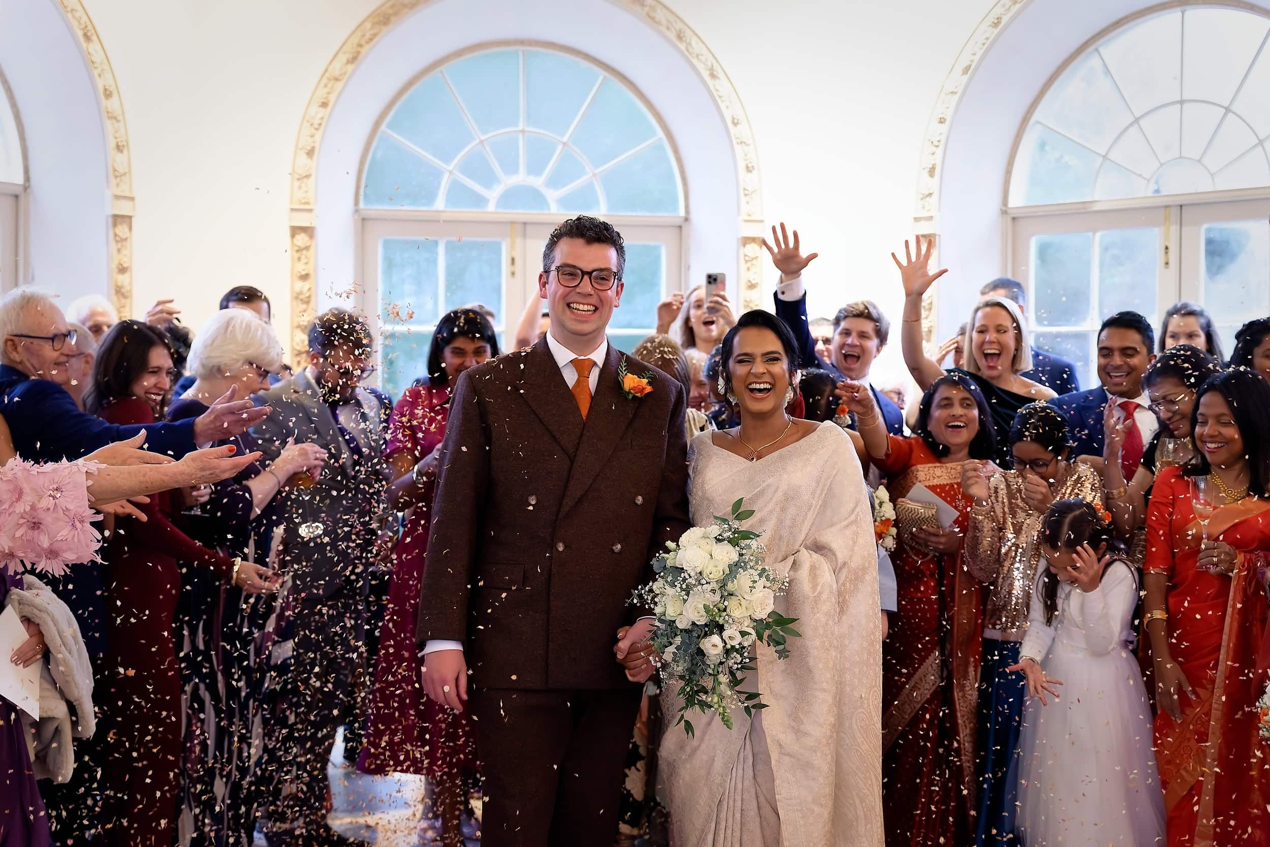 Bride and groom celebrating with confetti after the ceremony in the Vine Room at Northbrook Park wedding venue in Hampshire by Andy Kerr Photography