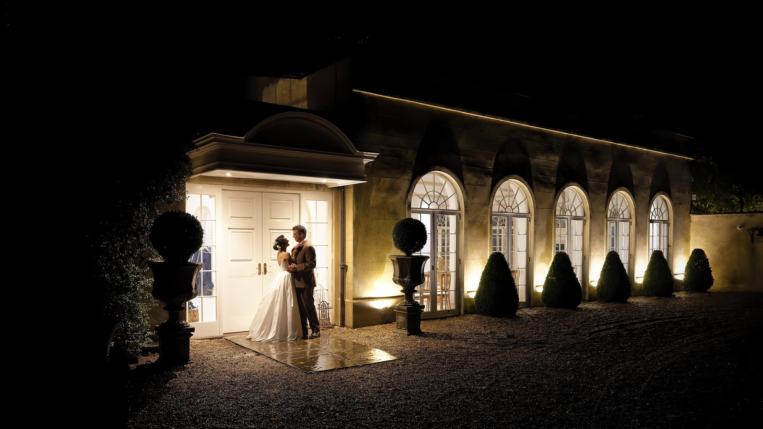 Atmospheric night portrait of bride and groom outside at the Vine Room entrance at Northbrook Park wedding venue in Hampshire by Andy Kerr Photography