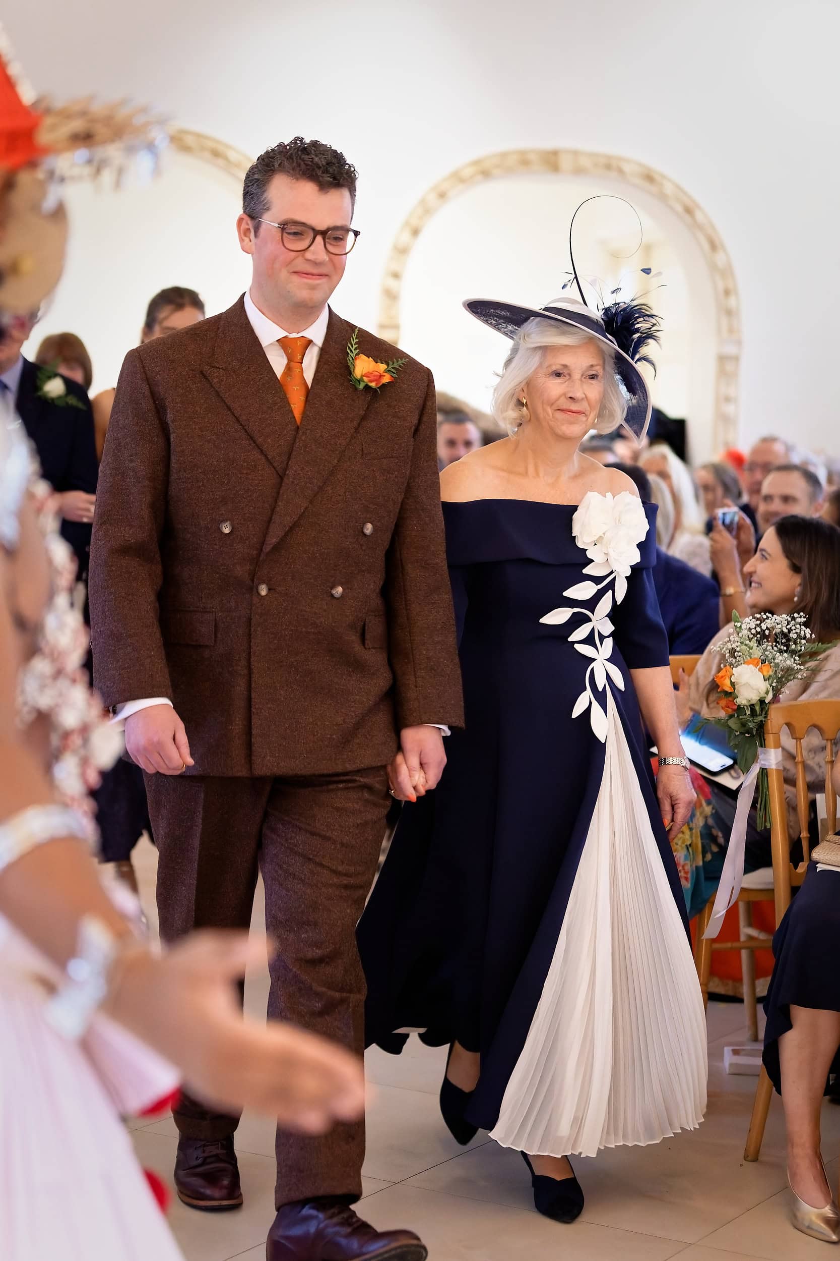 Groom walking down the aisle with his mother during the ceremony procession in the Vine Room at Northbrook Park wedding venue in Hampshire by Andy Kerr Photography