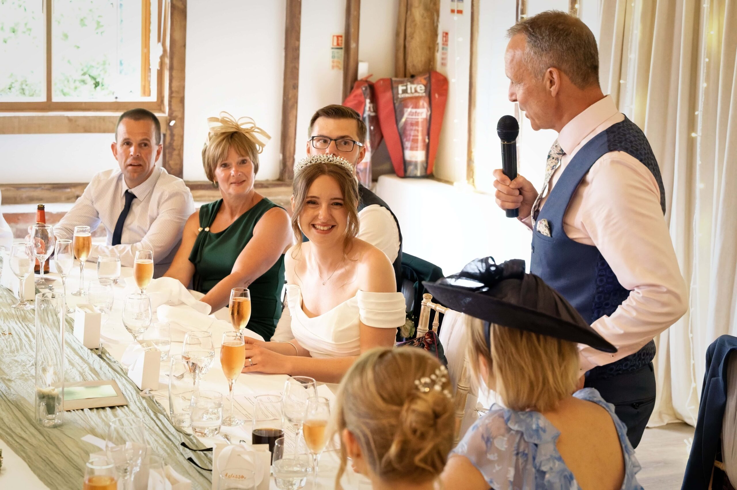 Fitzleroi Barn wedding photographer photo of guests reacting to the father of the bride's speech at the top table