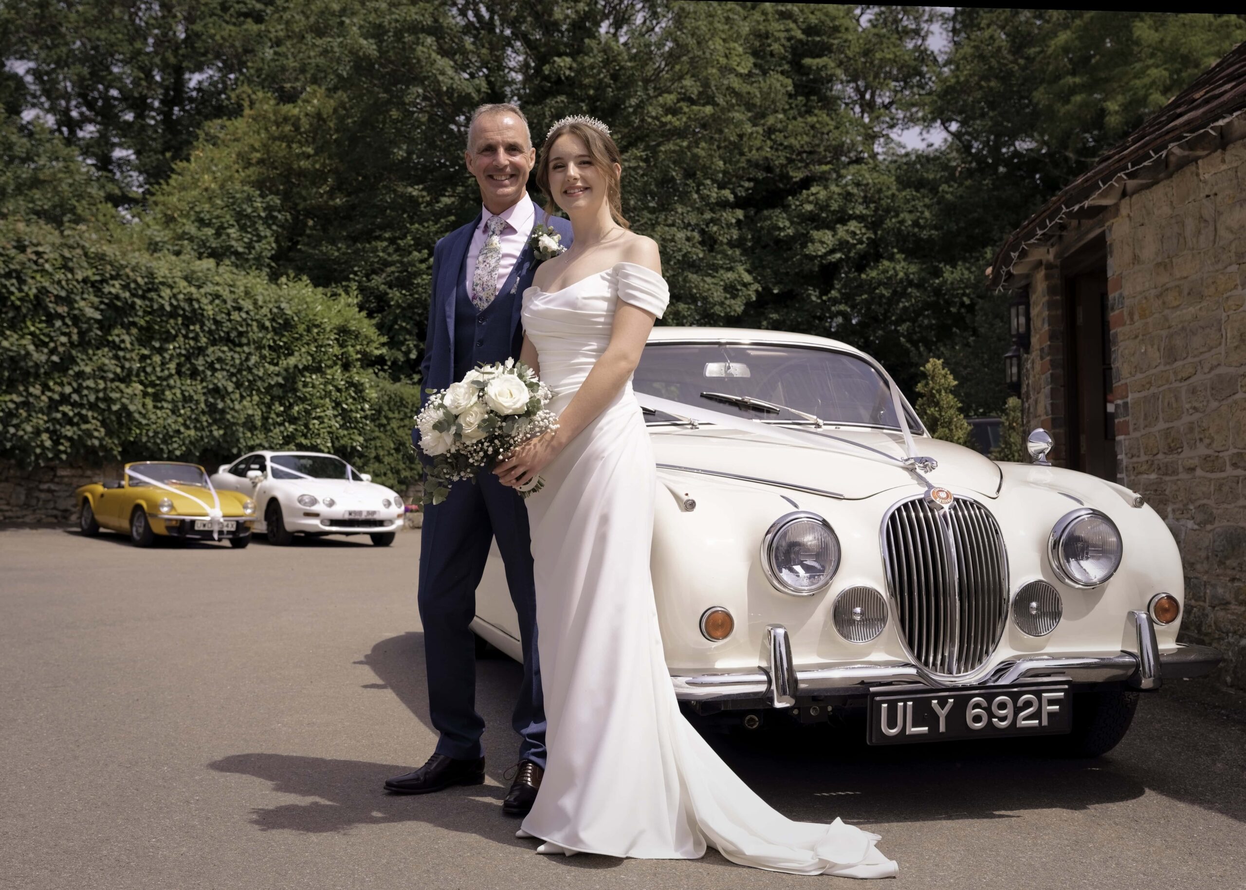 Fitzleroi Barn wedding photographer image of the bride and her father beside a vintage cream Jaguar wedding car