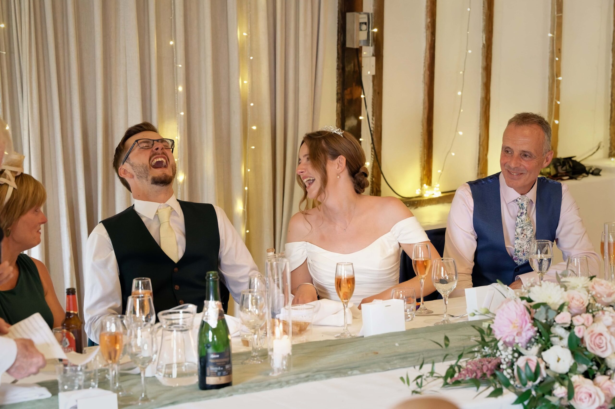 Fitzleroi Barn wedding photographer capturing the bride and groom laughing together during the speeches