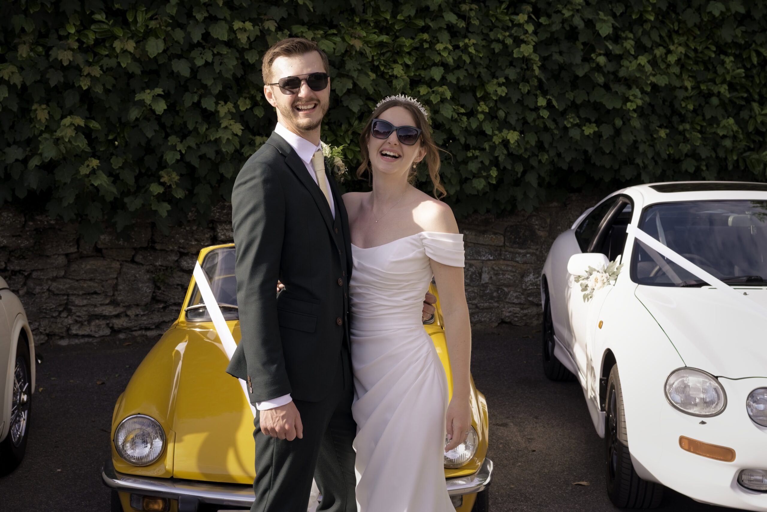 Fitzleroi Barn wedding photographer portrait of the couple laughing beside classic wedding cars