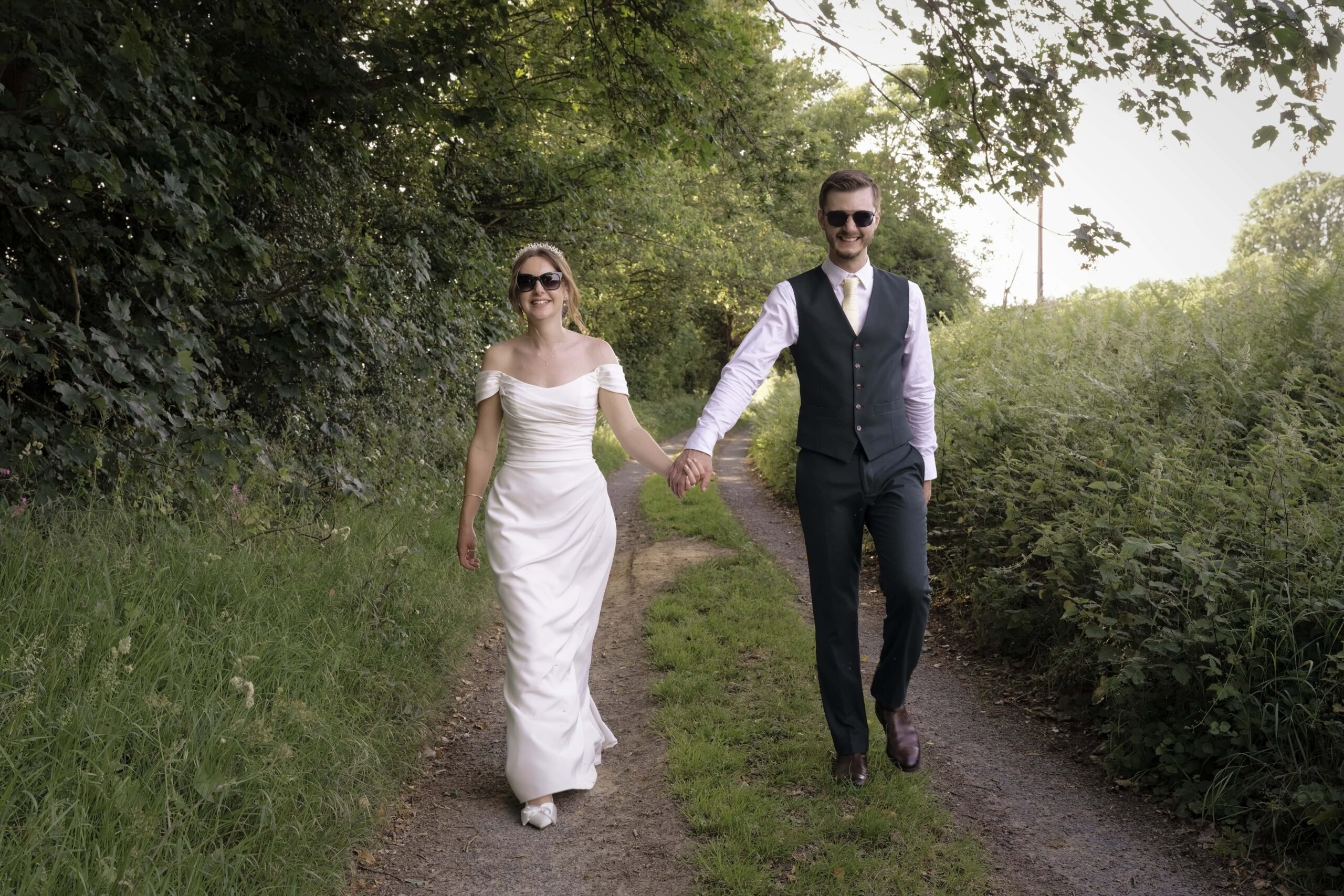 Fitzleroi Barn wedding photographer photo of the newlyweds walking hand in hand along a country lane
