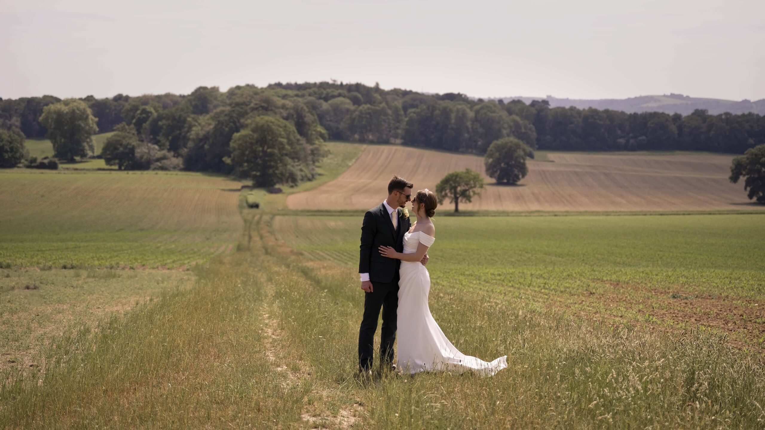 Fitzleroi Barn wedding photographer image of the couple embracing in an open countryside field