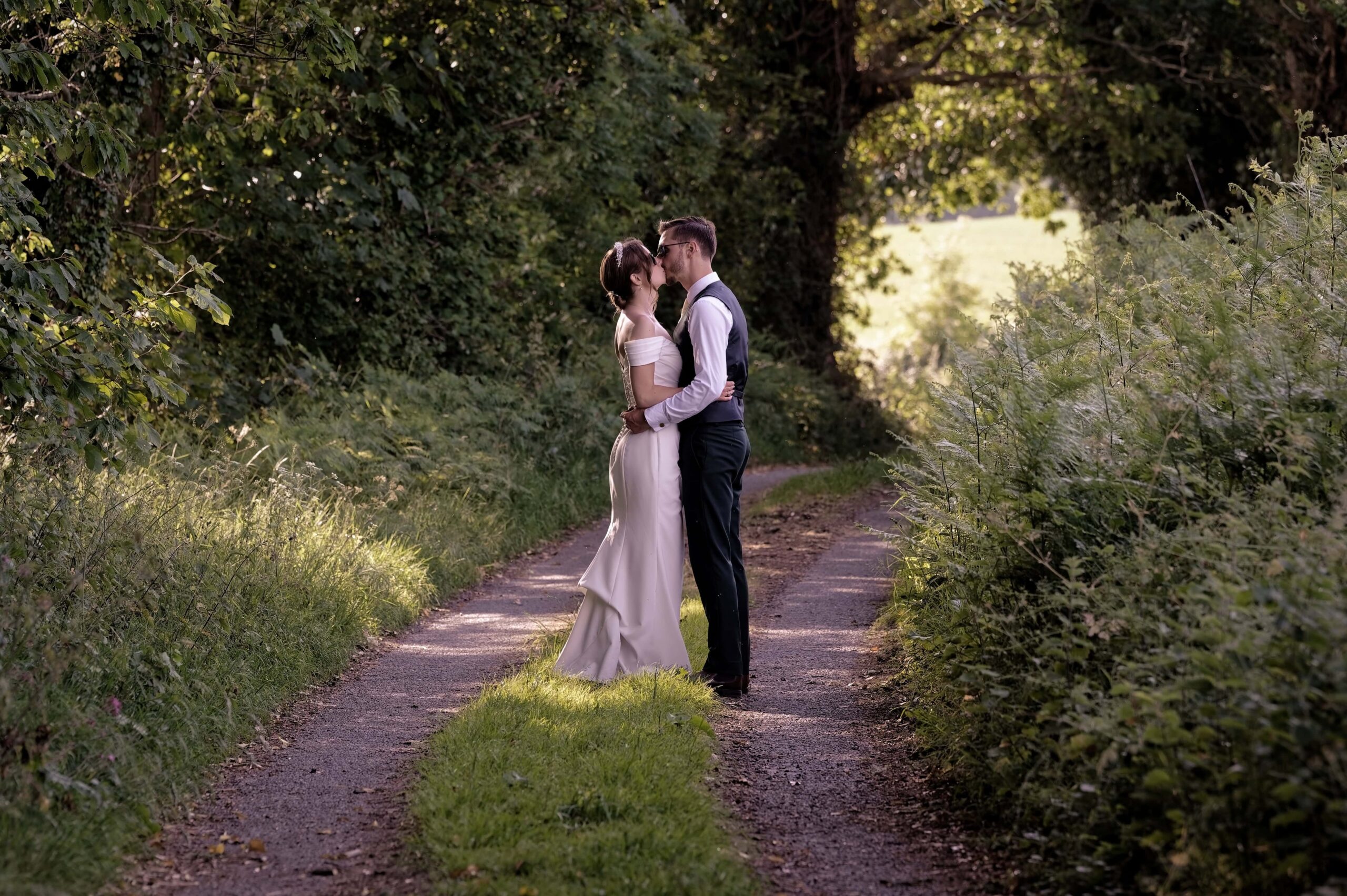Fitzleroi Barn wedding photographer capturing the couple's kiss on a quiet country lane at golden hour