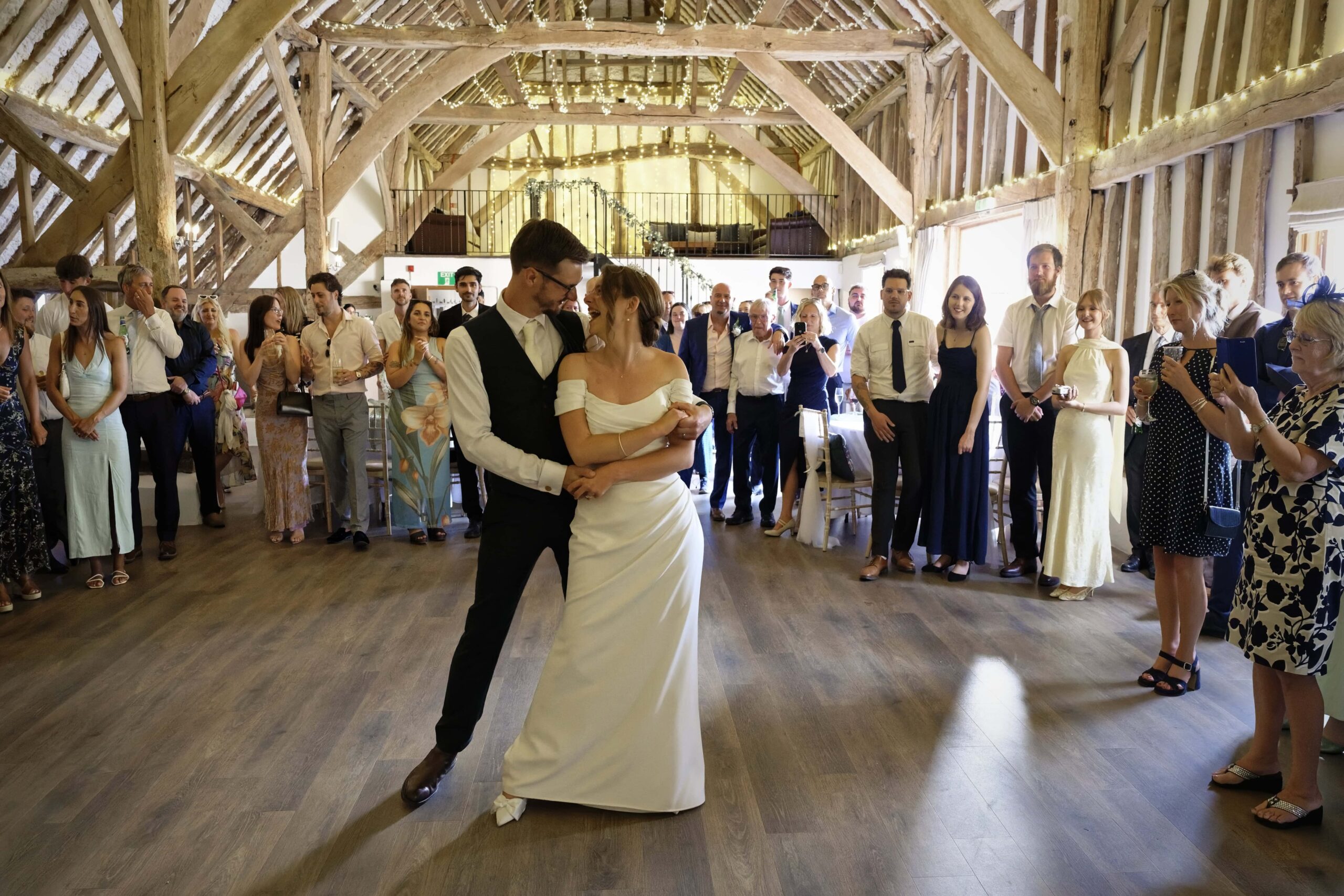 Fitzleroi Barn wedding photographer capturing an emotional first dance embrace surrounded by guests