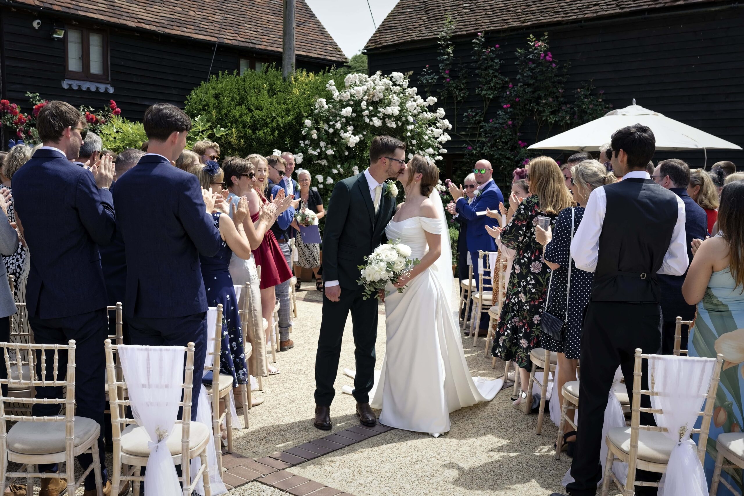 Fitzleroi Barn wedding photographer capturing the newlyweds' first kiss as guests applaud