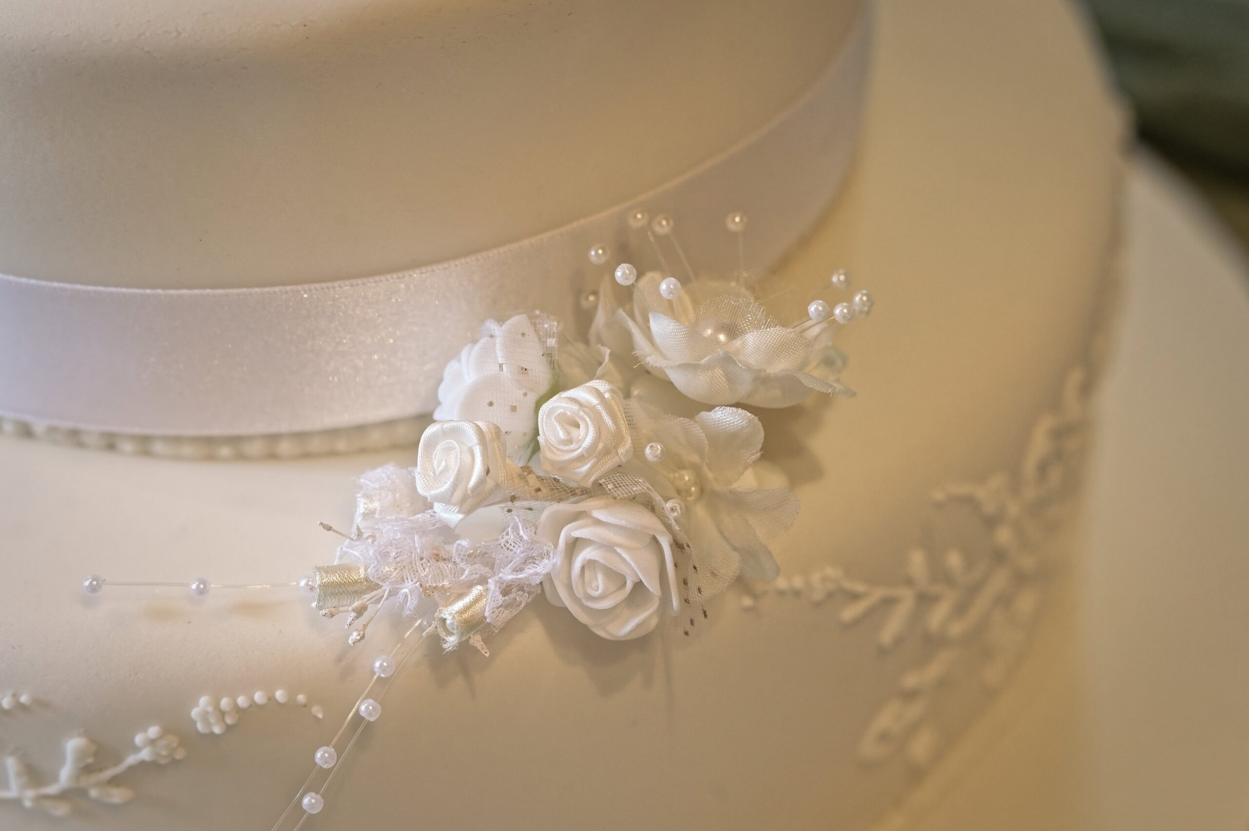 Fitzleroi Barn wedding photographer close-up detail shot of the wedding cake's fabric floral decoration