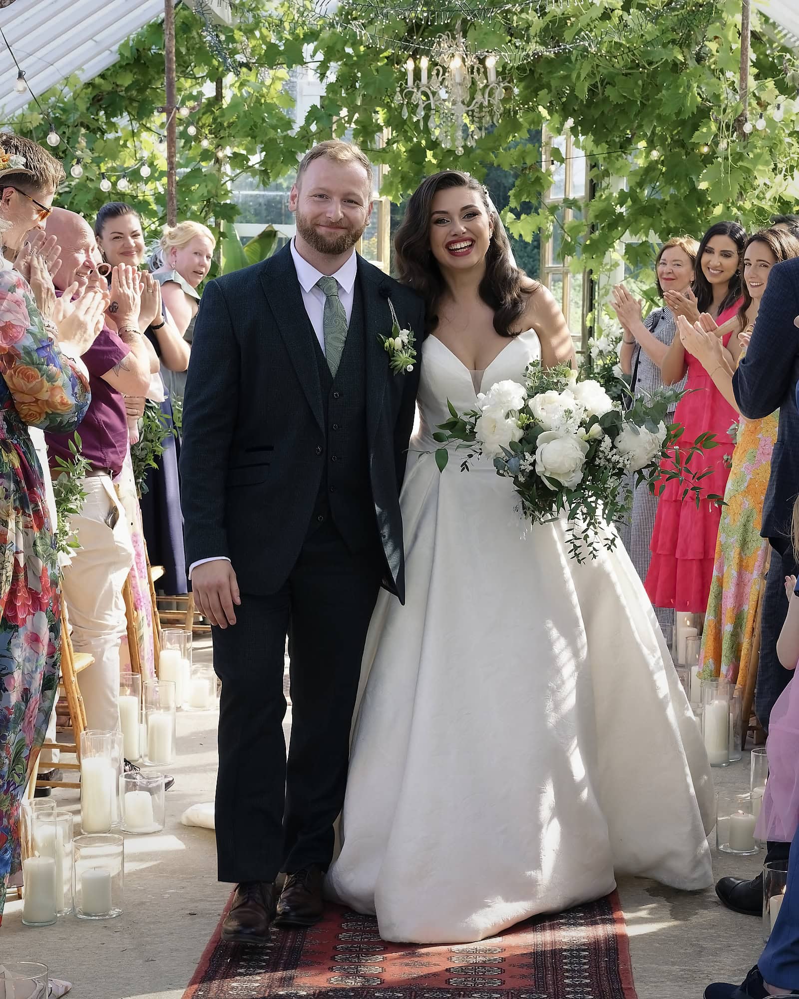 Newlyweds walking back down the aisle to applause from guests