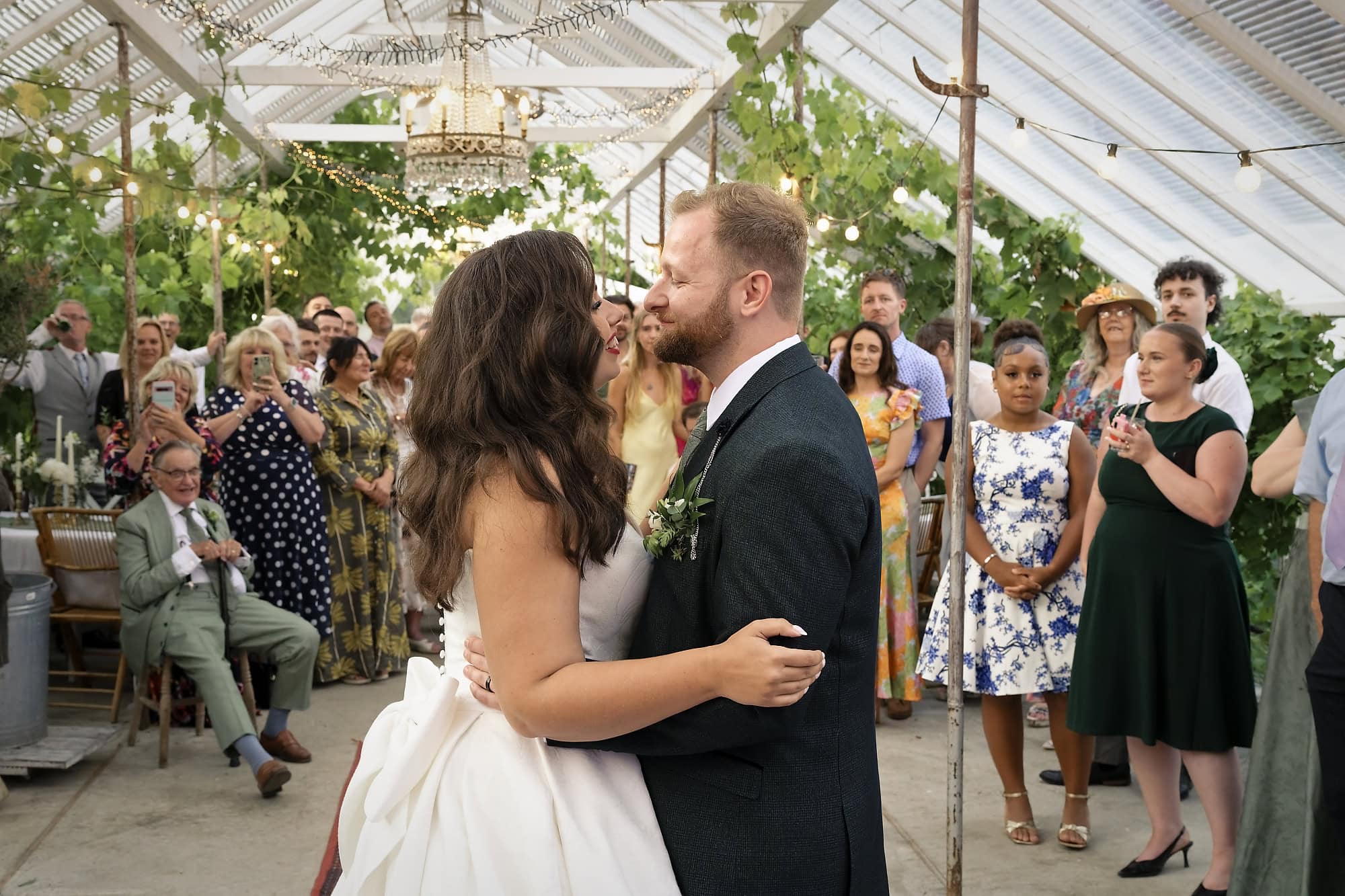Bride and groom sharing their first dance inside the vine-covered glasshouse