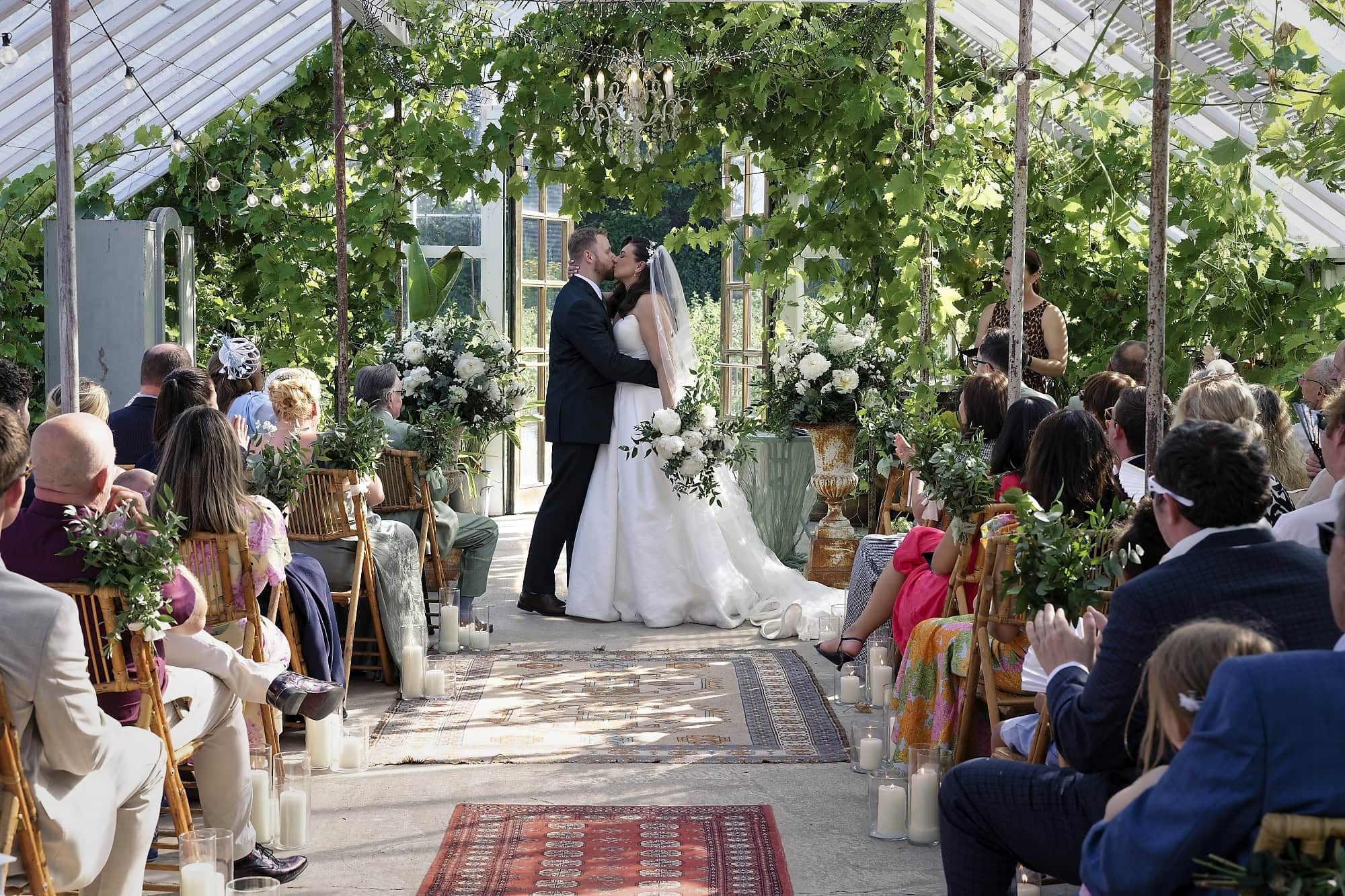 Bride and groom share their first kiss as newlyweds inside the glasshouse