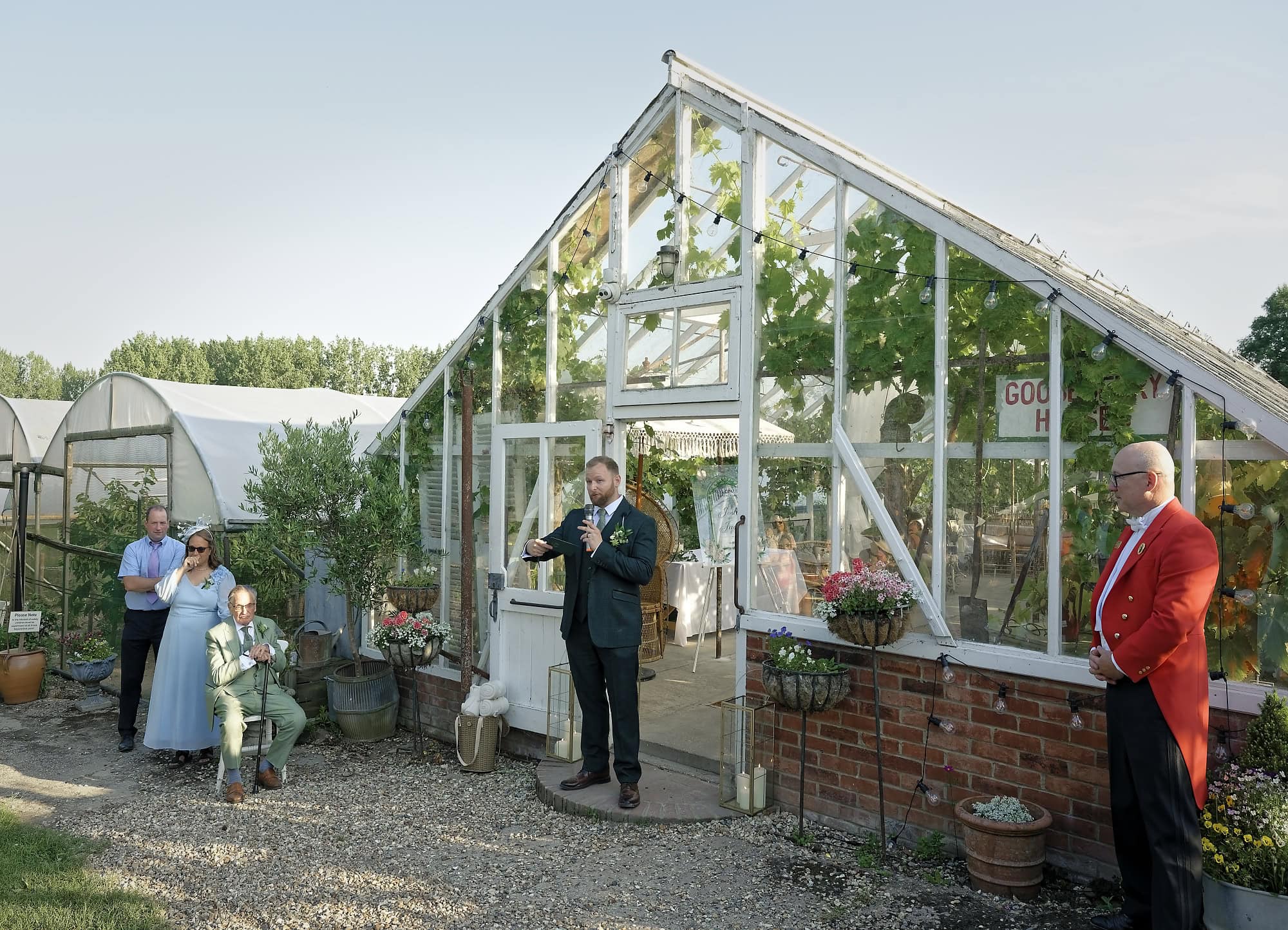 Groom giving his speech outside the Gooseberry House glasshouse with the toastmaster listening