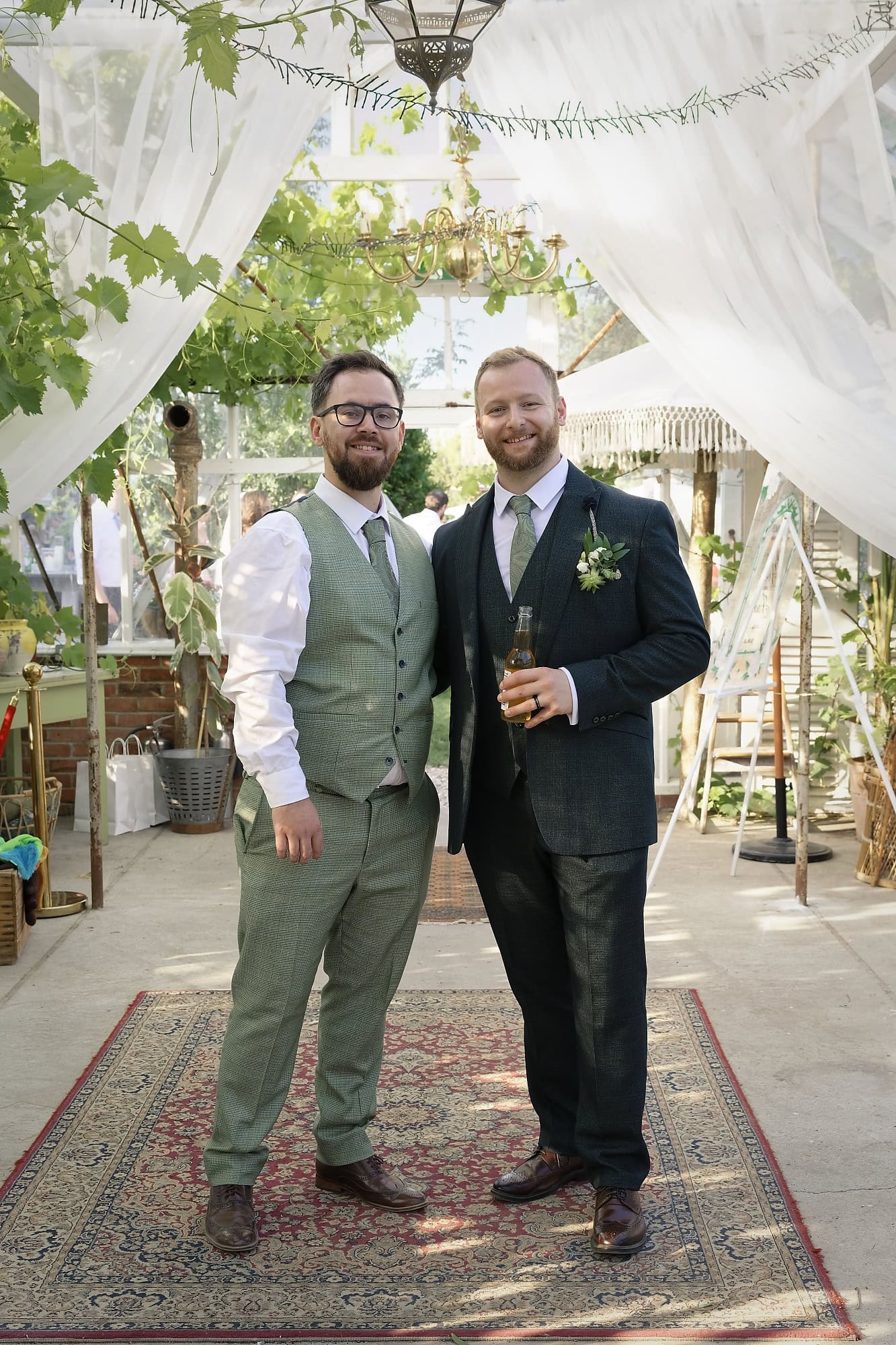 Groom and best man posing together under the glasshouse's macrame canopy