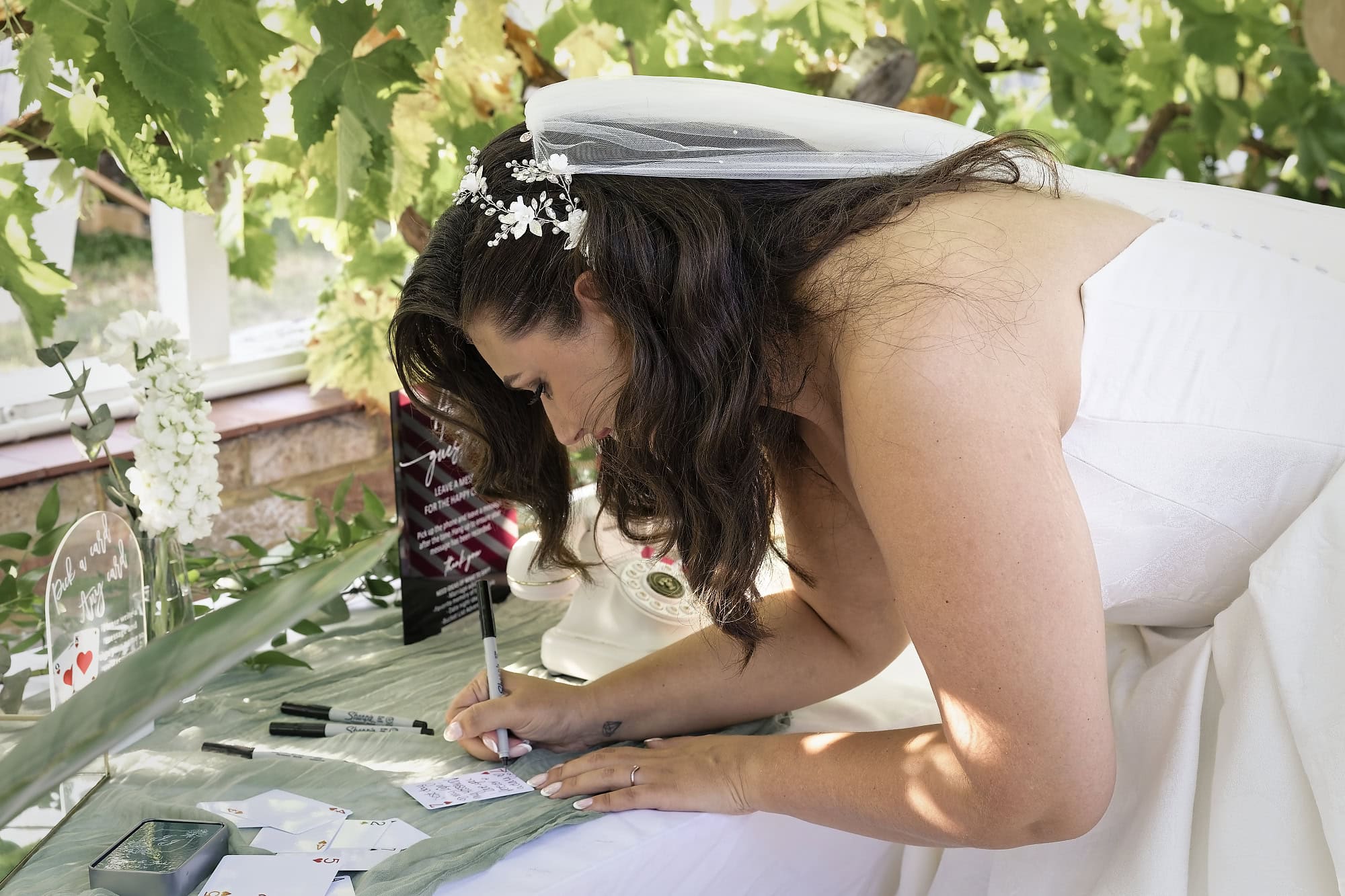Bride signing a card at the wedding's pick-a-card guest book table