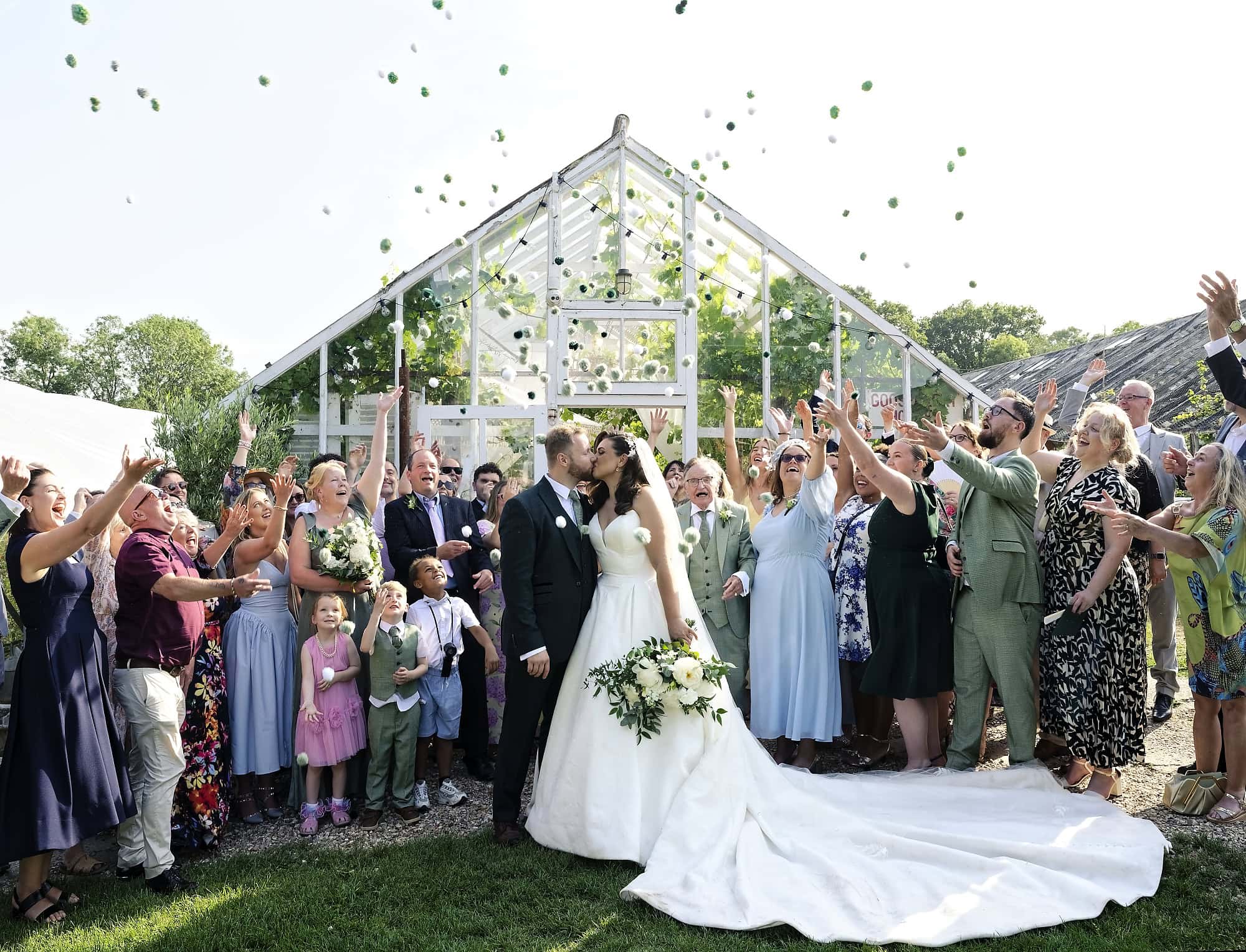 Bride and groom kissing during the pompom send-off in front of Gooseberry House