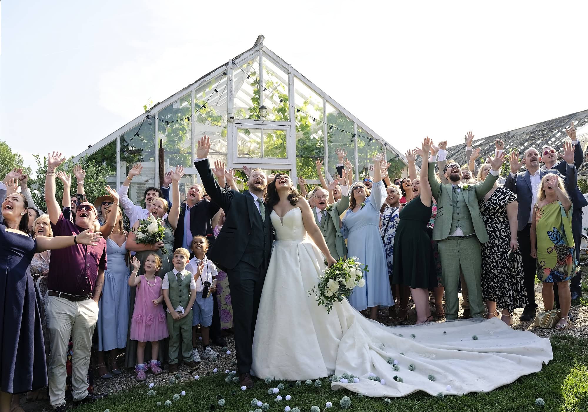 Wedding guests waving at drone in front of the glasshouse