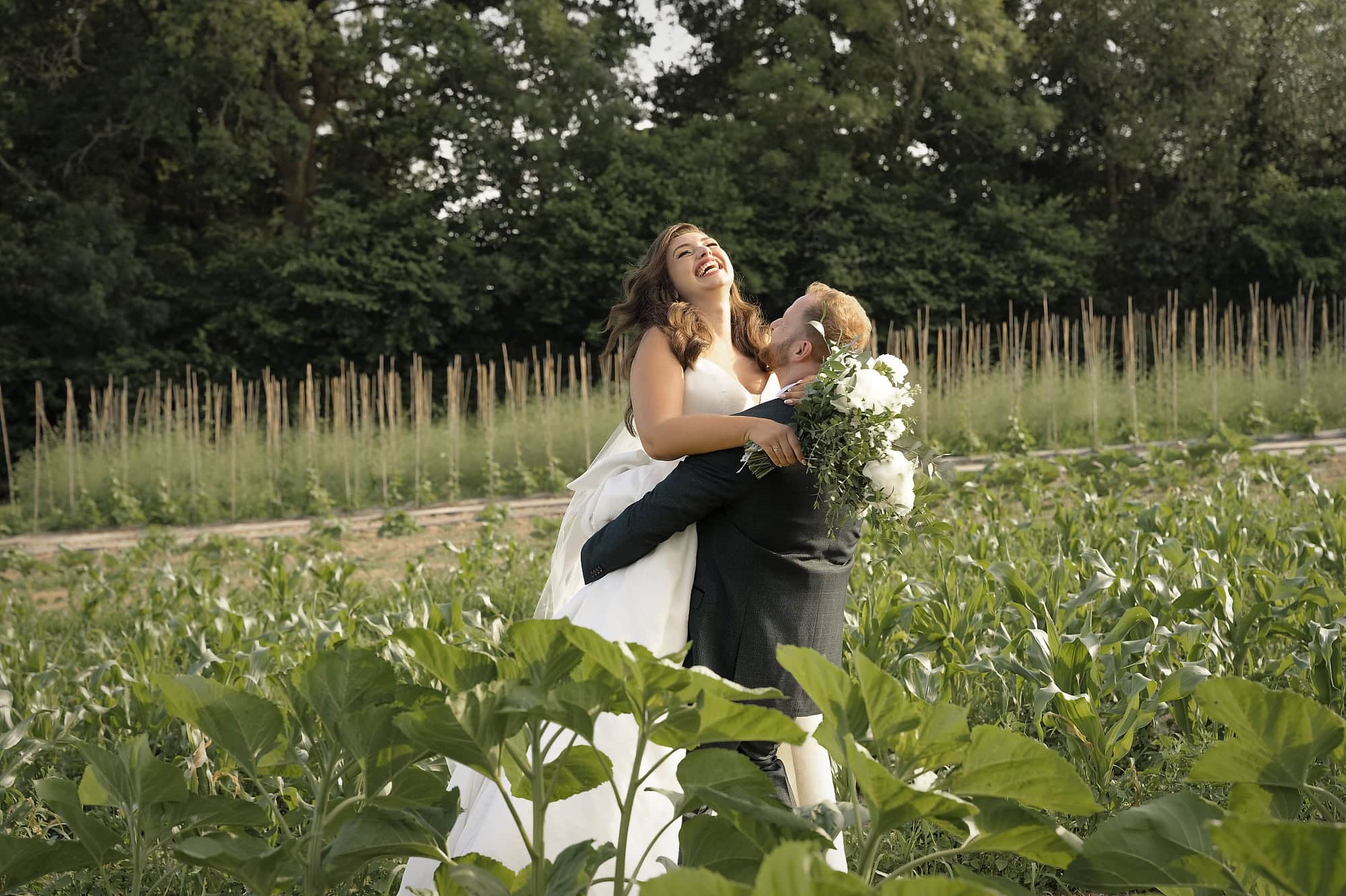 Groom lifting his bride in the sunflower field behind Gooseberry House