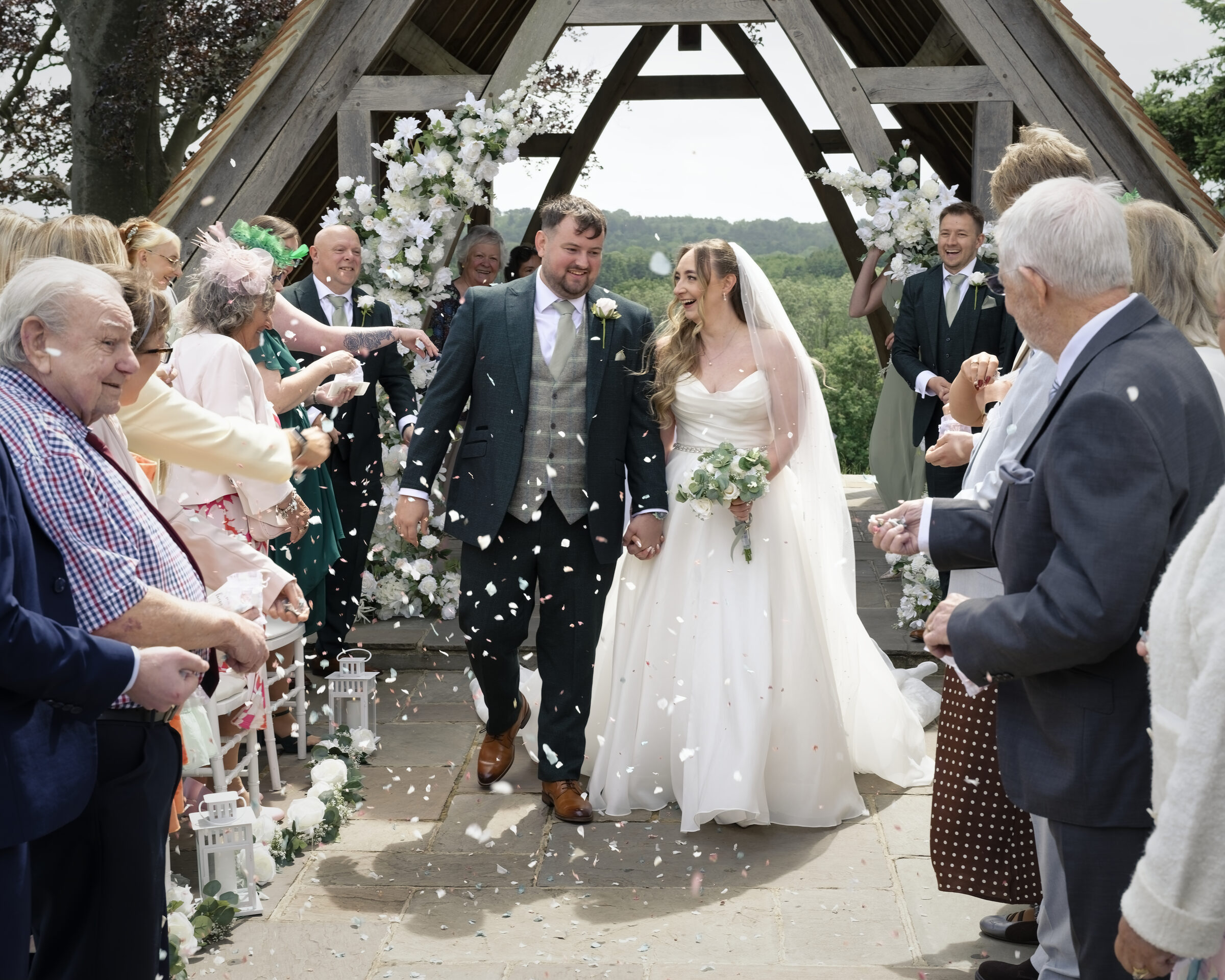 Newlyweds walking through a confetti shower after their wedding ceremony at Highley Manor