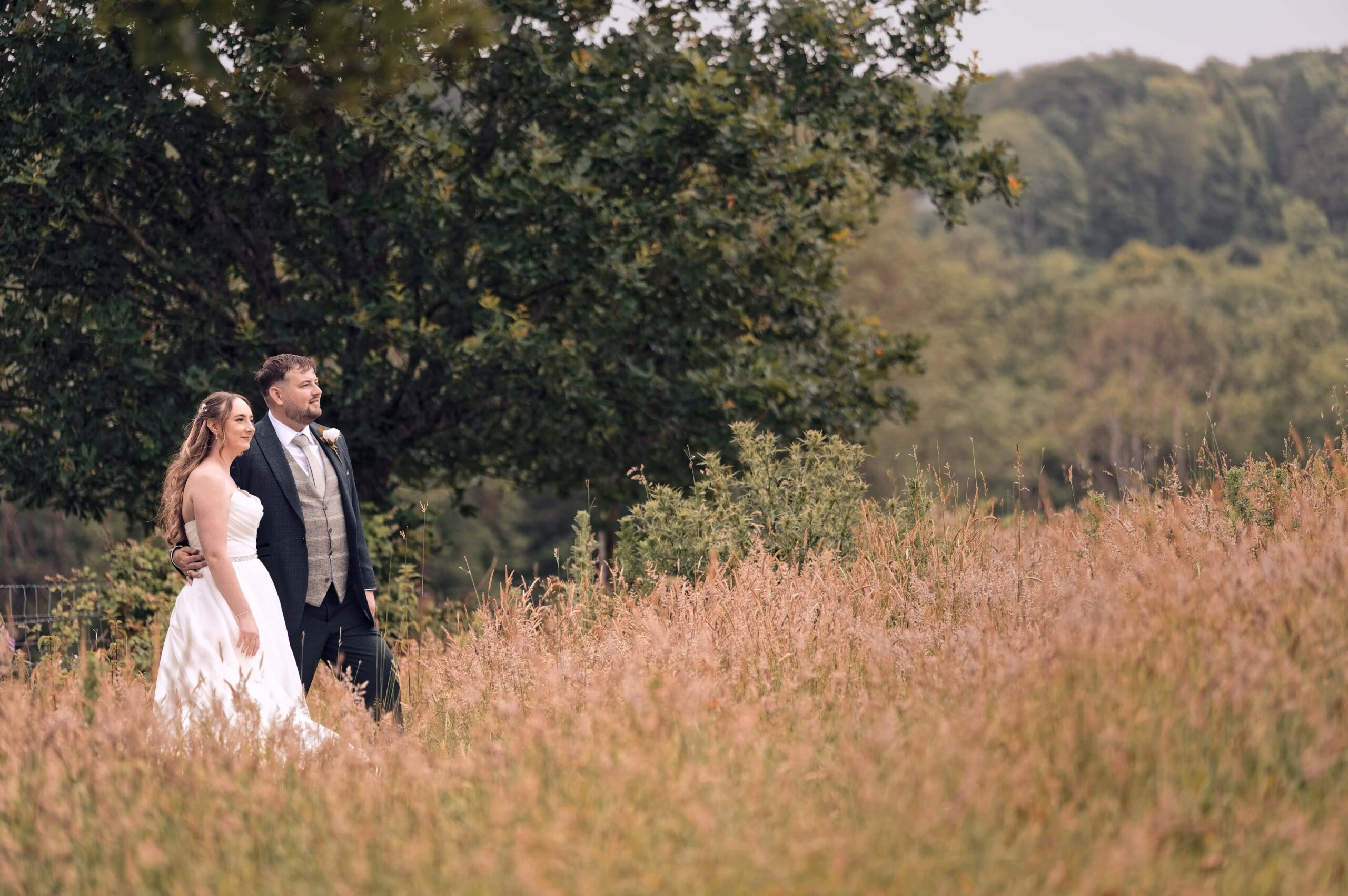 Bride and groom walking through golden grass in the grounds of Highley Manor
