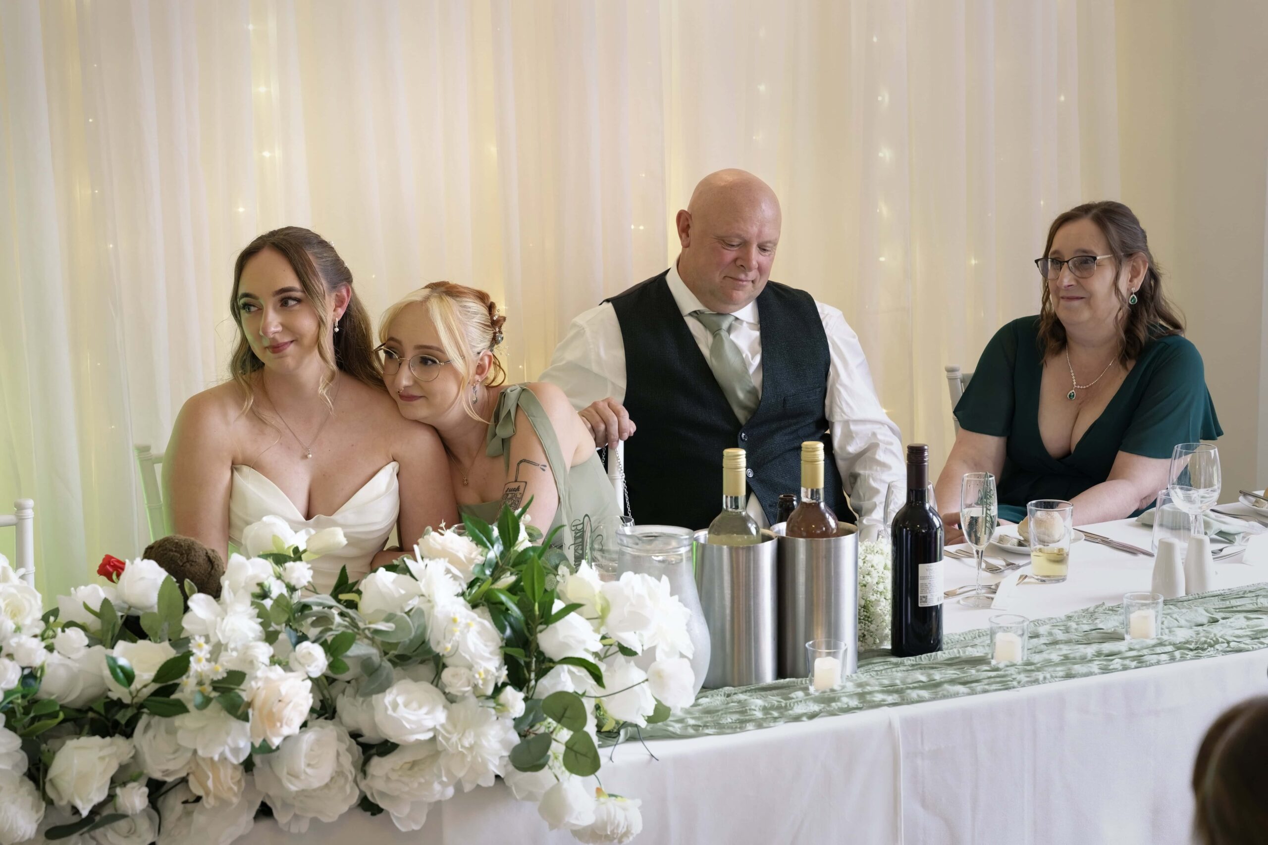 Bride and bridesmaids sharing a candid moment at the top table during the Highley Manor reception