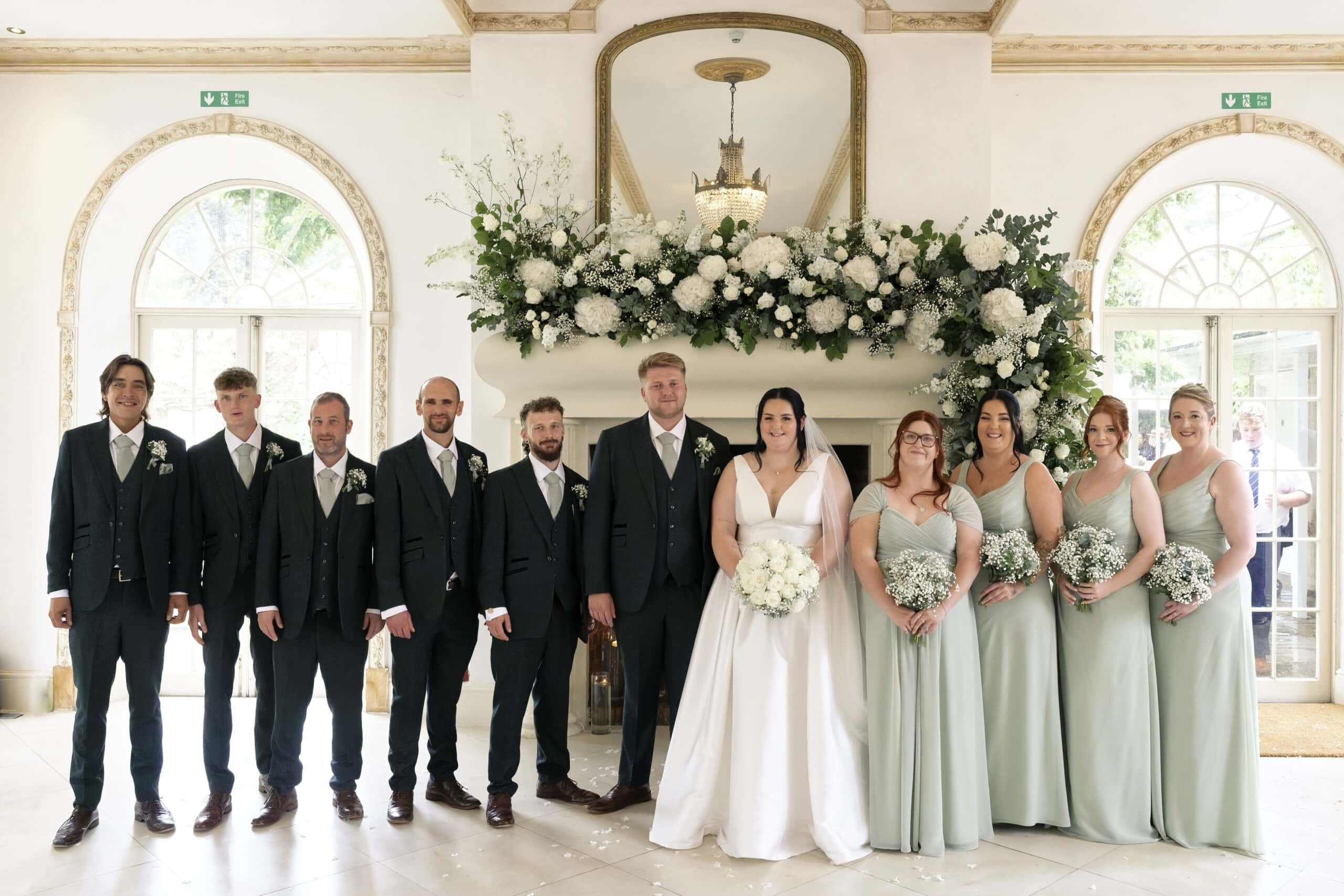 Bridal party gathered around the flower-dressed fireplace