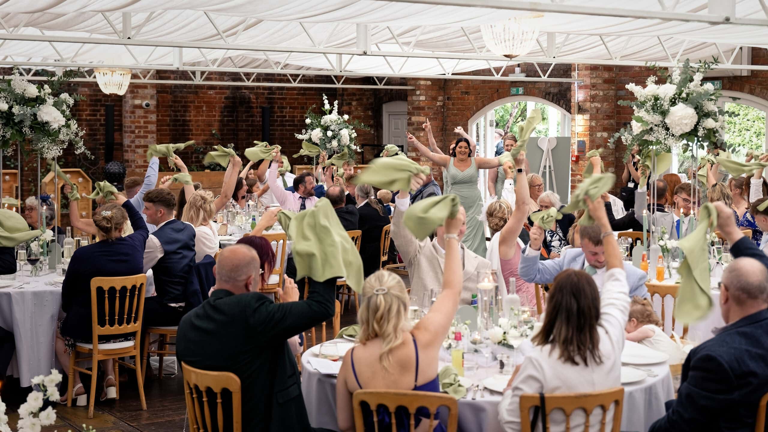 Guests waving green napkins as the bridal party enters the wedding breakfast room