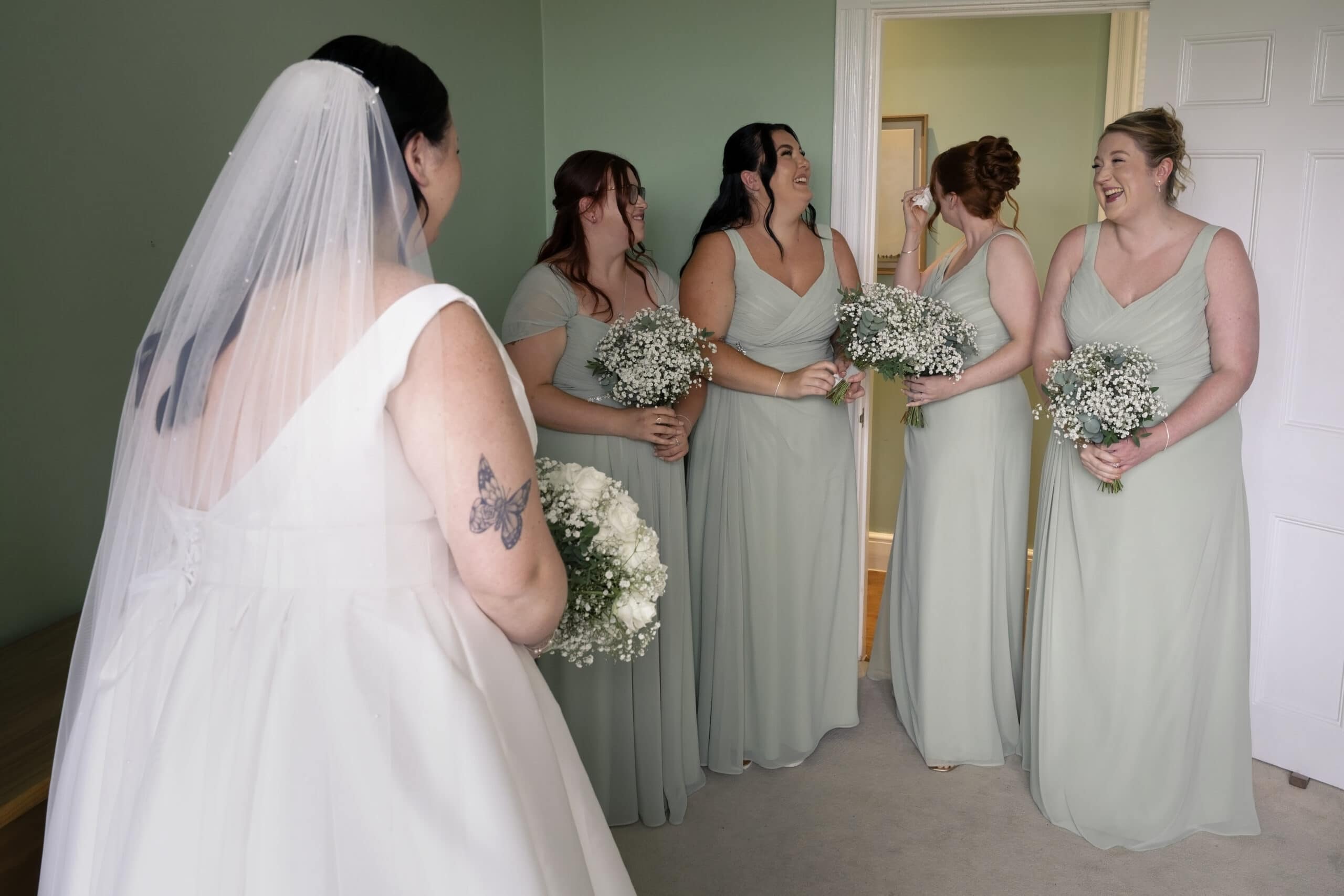Bridesmaids in sage green dresses holding white bouquets