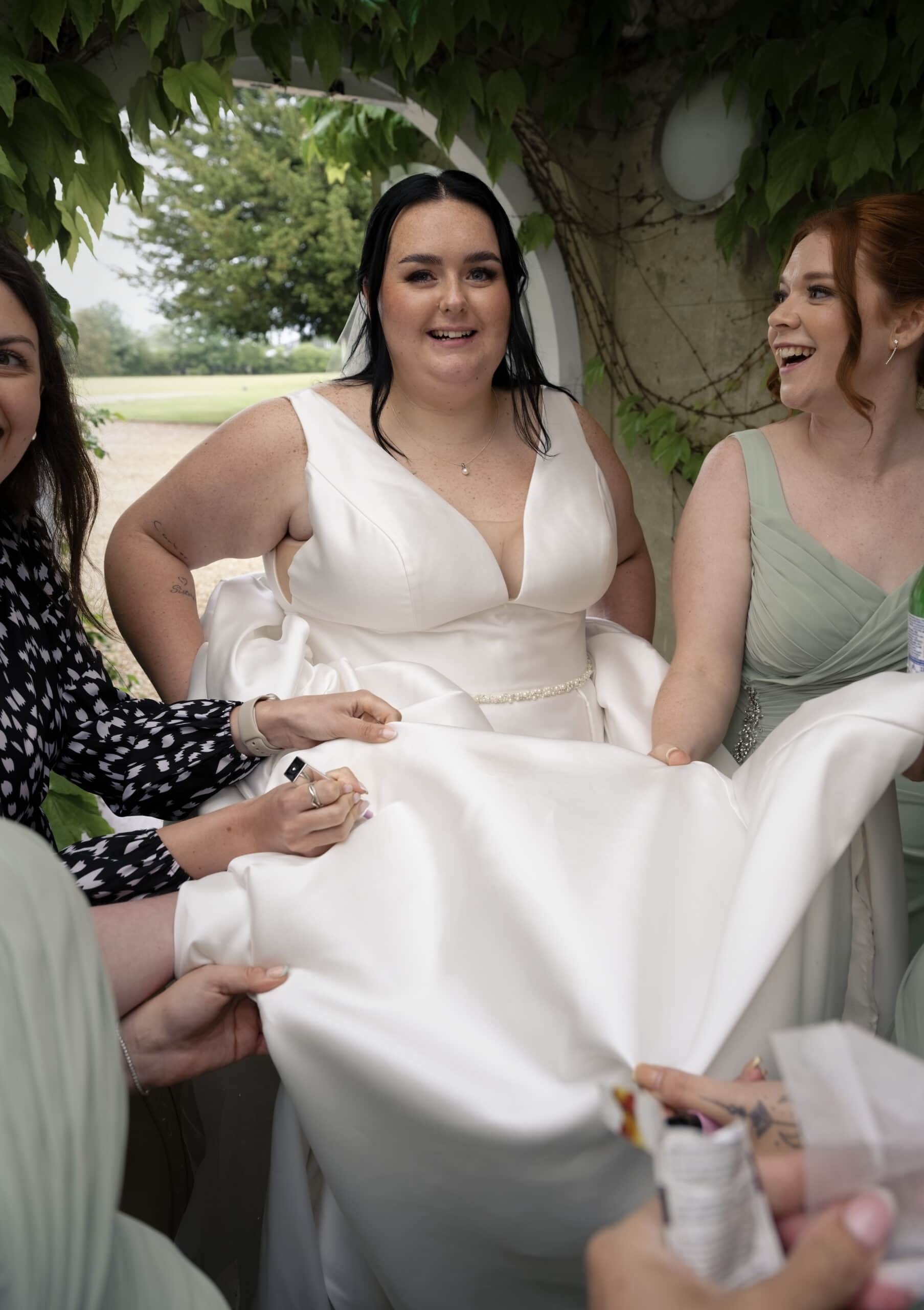 Bridesmaids helping Meghan remove a mark from her dress after the wedding breakfast