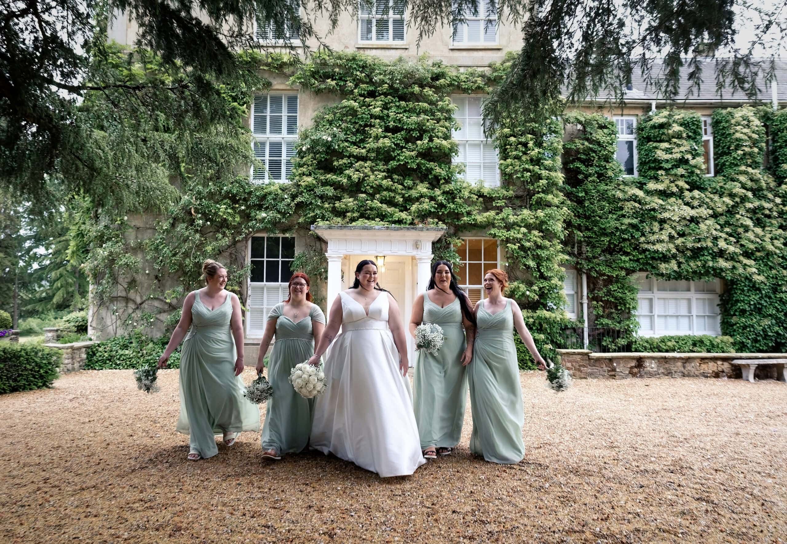 Bride and bridesmaids walking outside the main house in the evening
