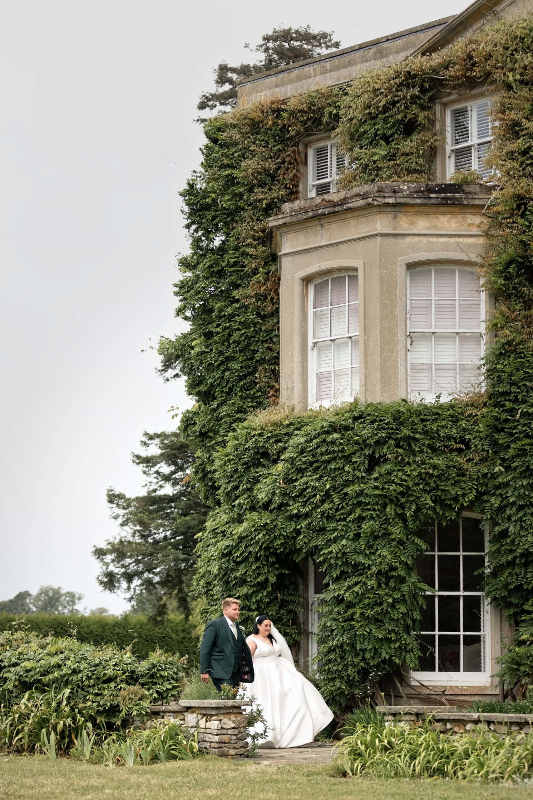 Bride and groom beside the ivy-covered house